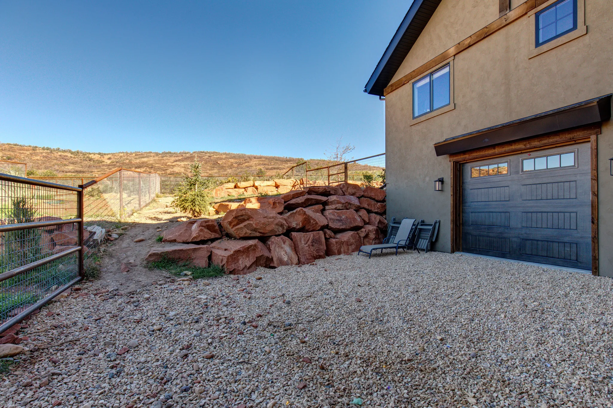 Stucco exterior featuring a wood-beam accent, a modern garage door with upper window inserts, and exterior wall sconce lighting