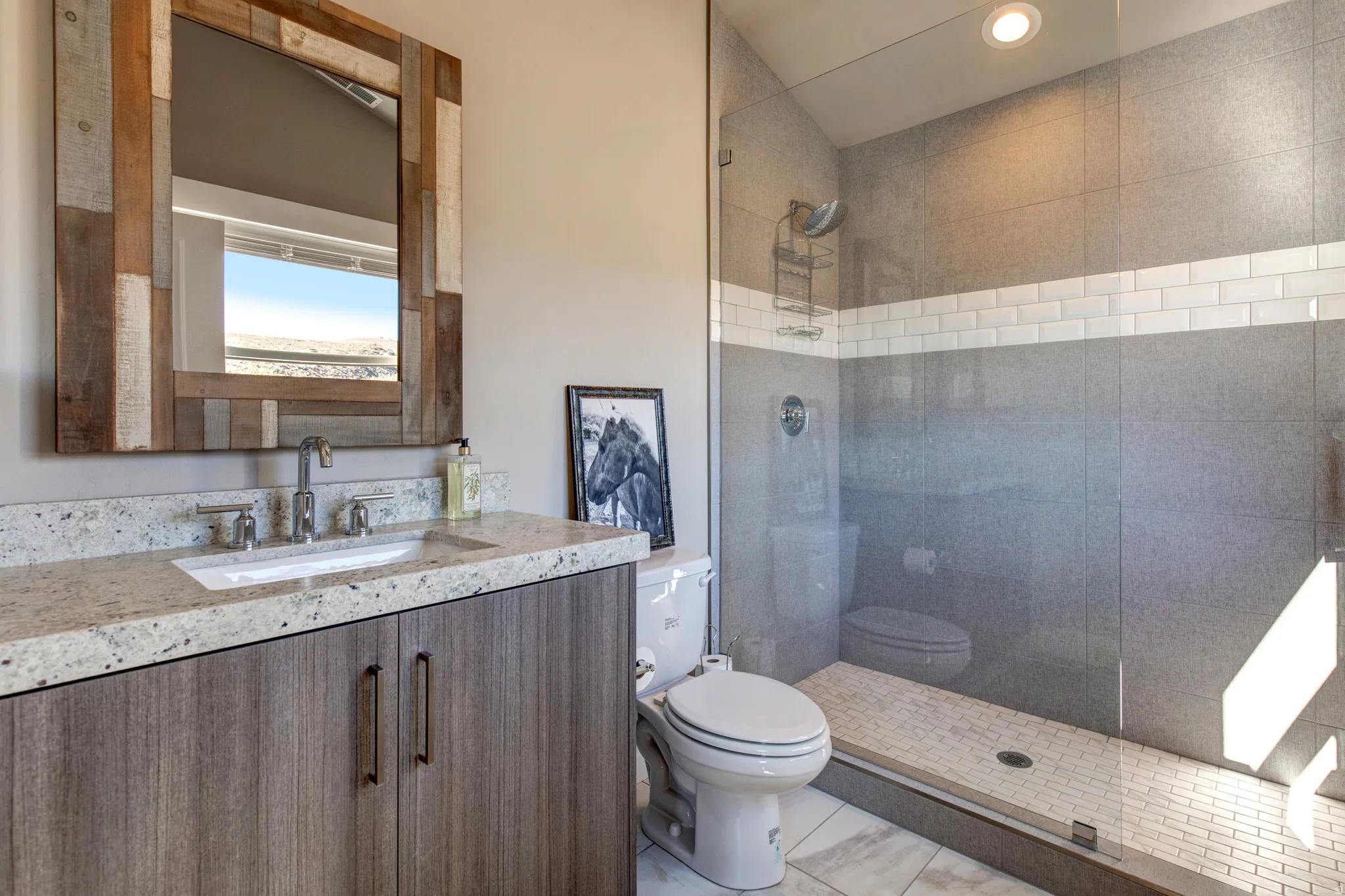 Modern bathroom featuring a wood-finish vanity with a light speckled countertop and undermount sink