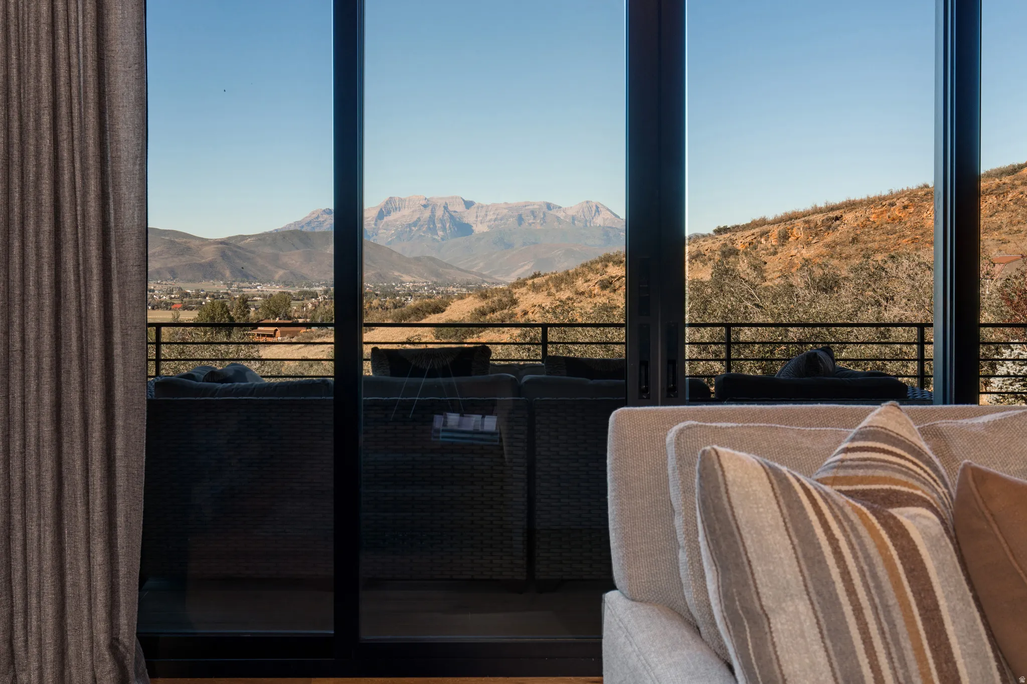 Floor-to-ceiling glass doors opening onto an exterior balcony with metal railing
