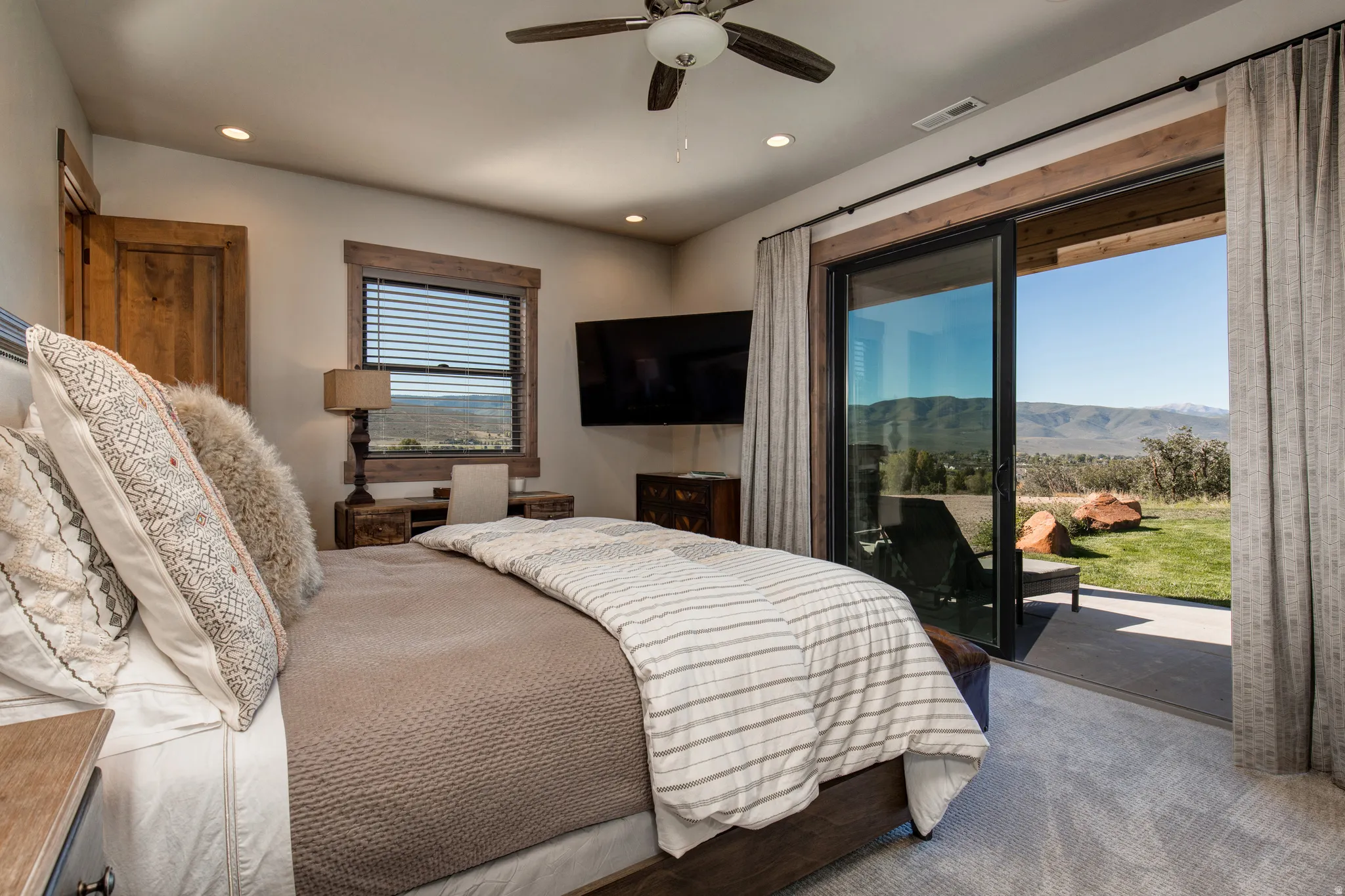 Spacious room featuring wood-finish door and window trim, a ceiling fan with light fixture, recessed lighting, and a wall-mounted television