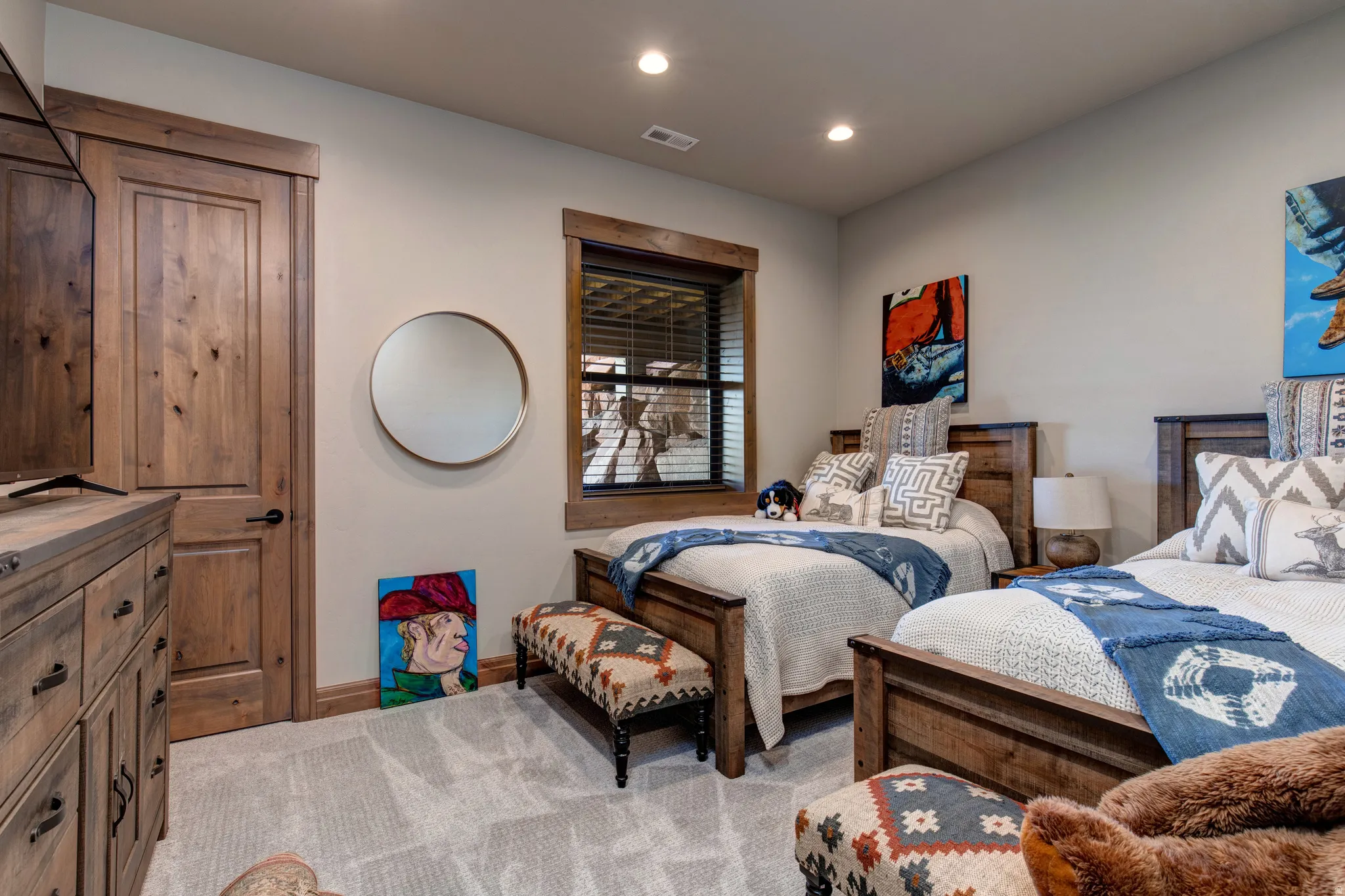 Carpeted room featuring two wood-frame beds, a built-in wood dresser, and a wood panel door