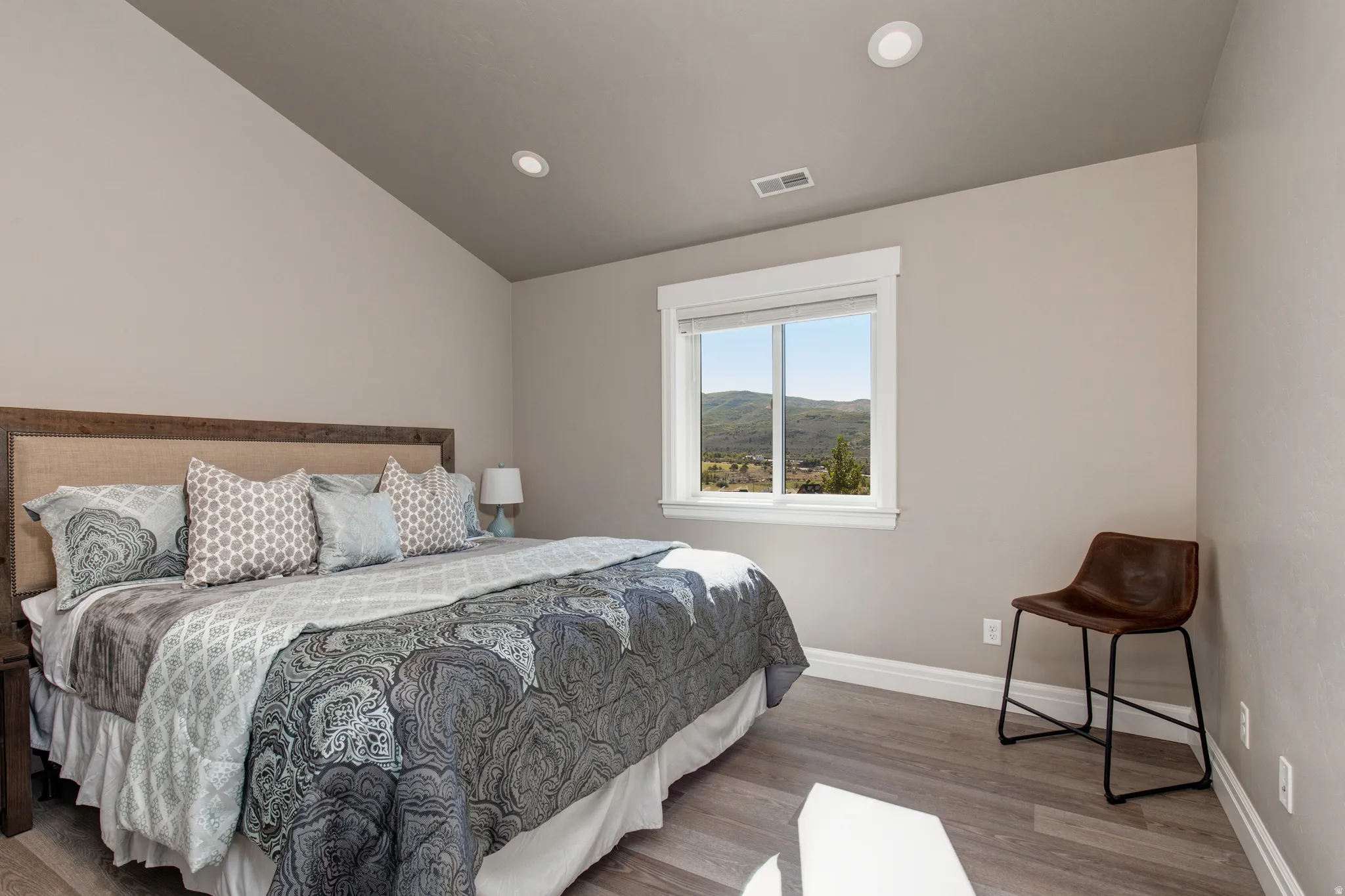 Spacious bedroom featuring wood-finish flooring, a vaulted ceiling, and recessed lighting