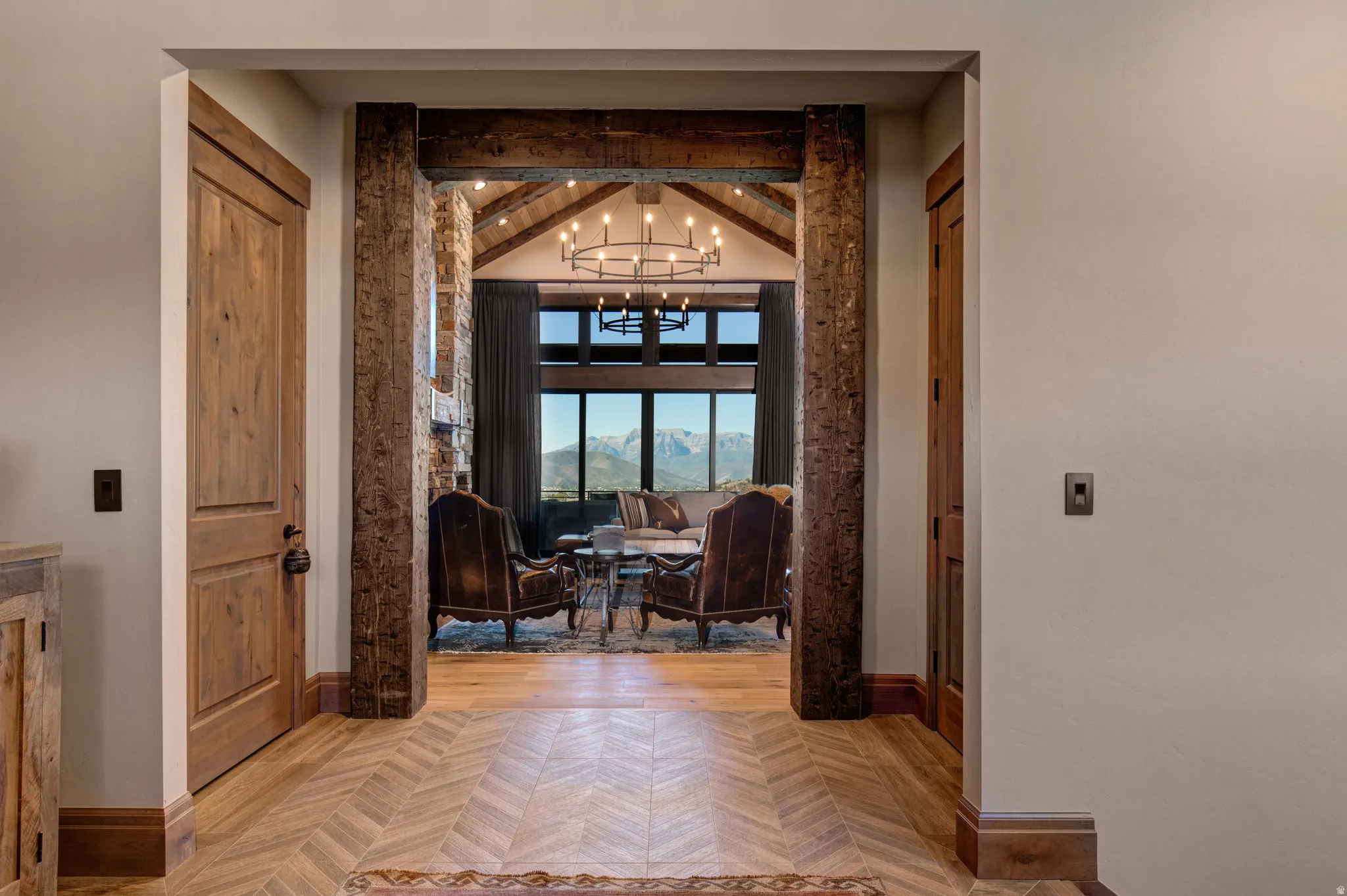 Herringbone wood-finish flooring extending into a spacious living area with exposed wooden beams and a vaulted ceiling