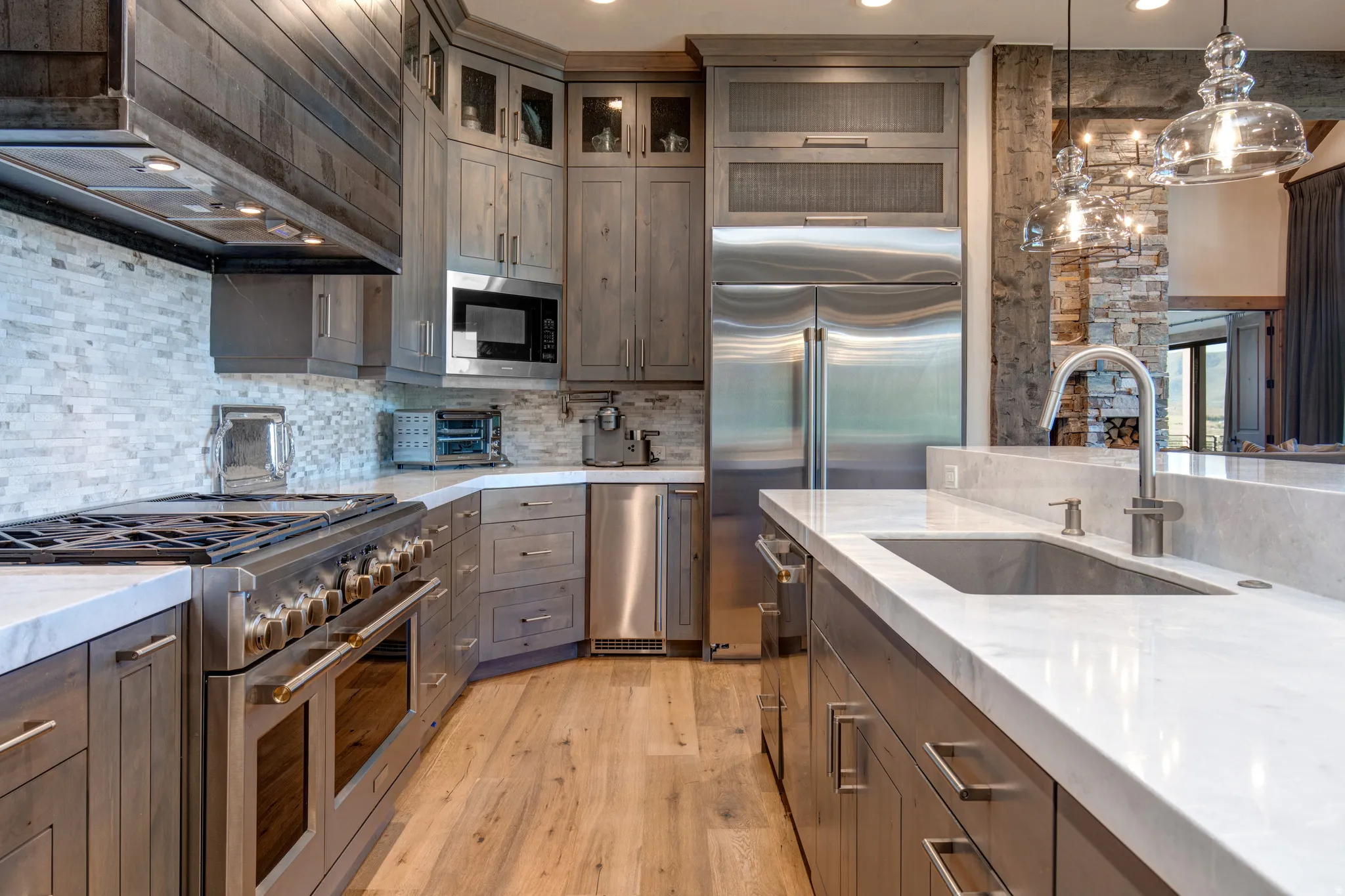 Gourmet kitchen featuring a professional-grade range, full-size stainless steel refrigerator, built-in microwave, light wood-finish cabinetry, and white countertops
