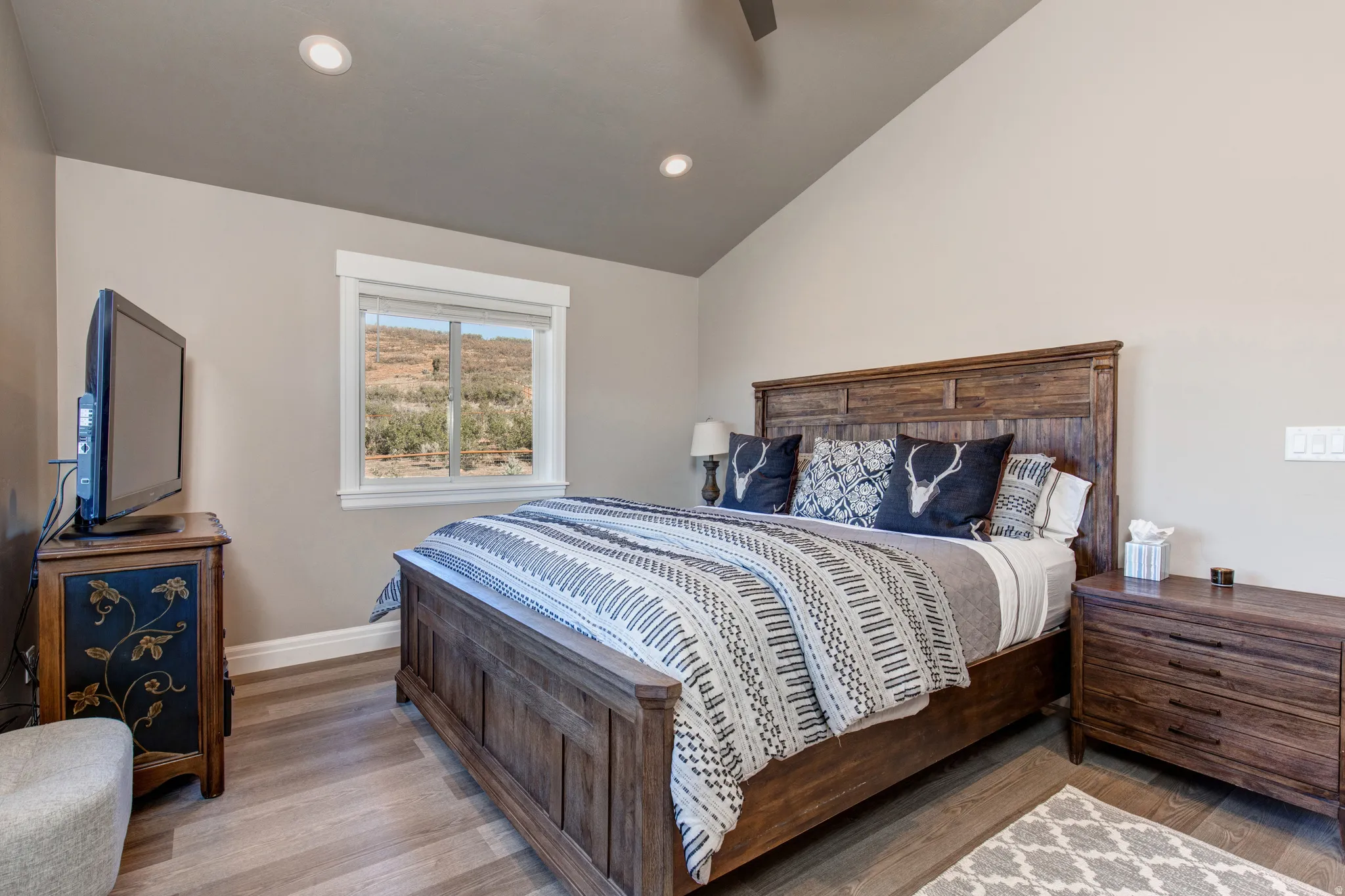 Spacious room featuring wood-finish flooring, recessed lighting, and a vaulted ceiling