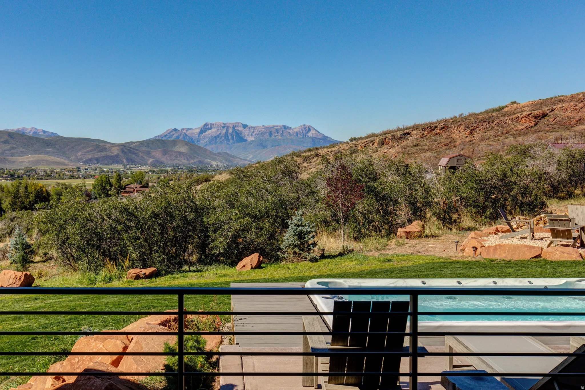 Outdoor deck featuring a built-in spa, horizontal metal railing, and composite decking