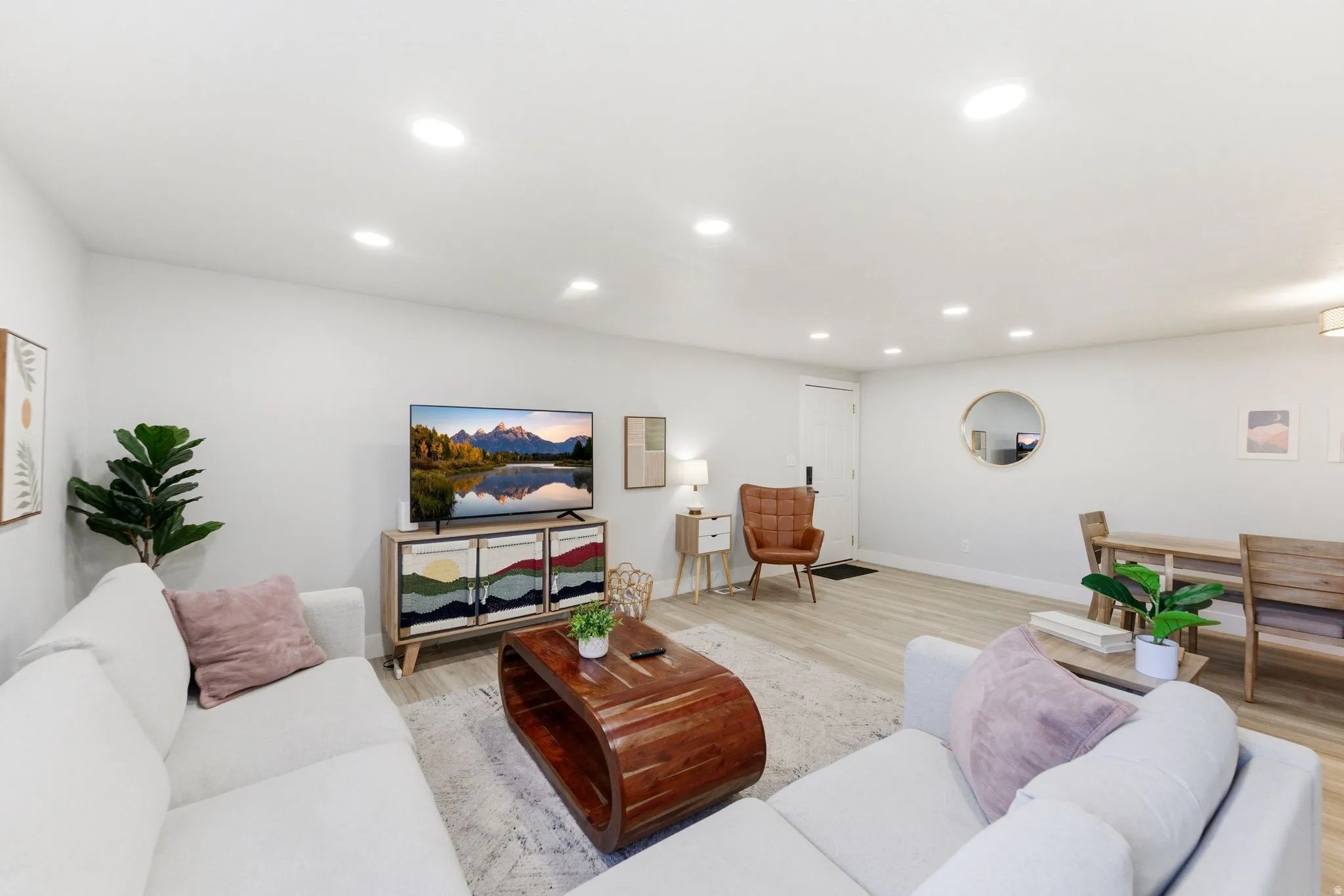 Open-concept living area with light wood-finish flooring, recessed lighting, white walls, a built-in media console, and a dining area