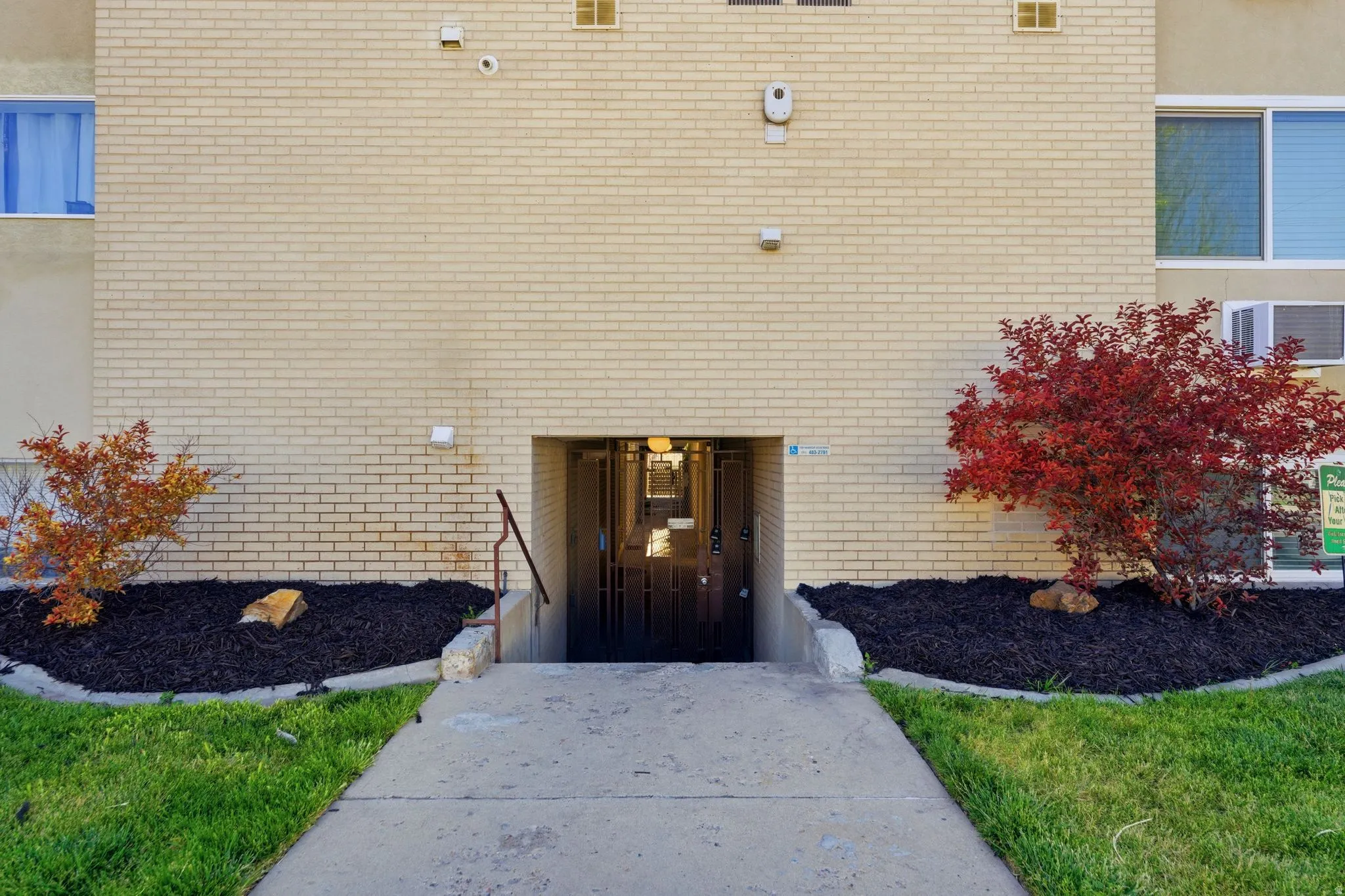 Cream-colored brick exterior featuring a recessed entry with security doors