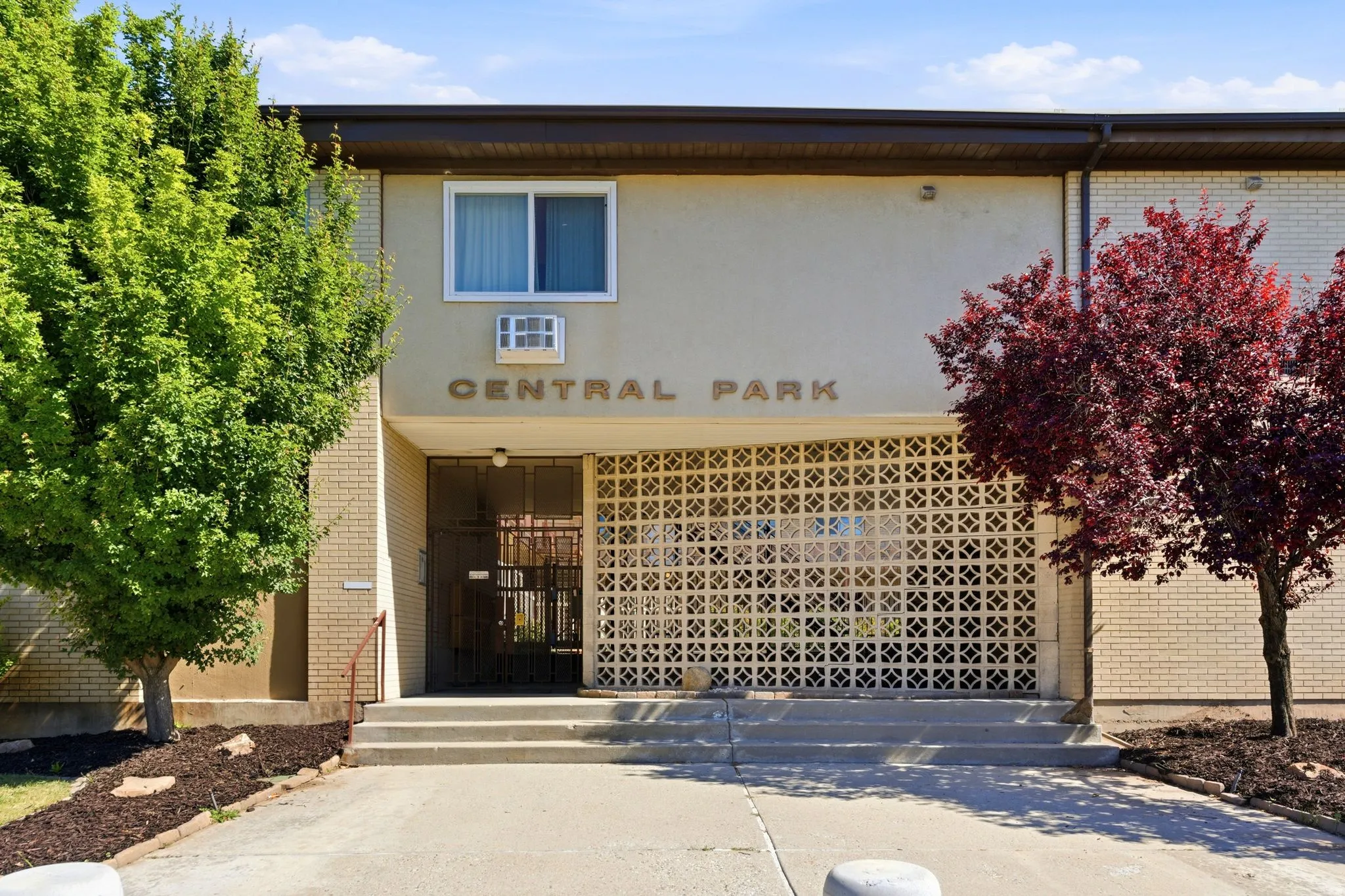 Building entrance featuring a security door, decorative block screen, and prominent signage