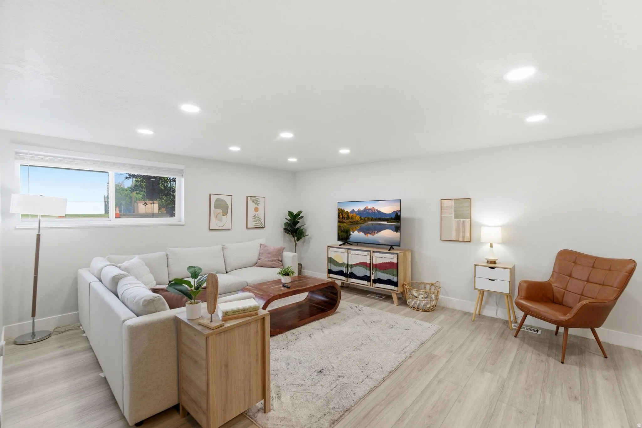Bright, open-concept living space with recessed lighting and light wood-finish flooring