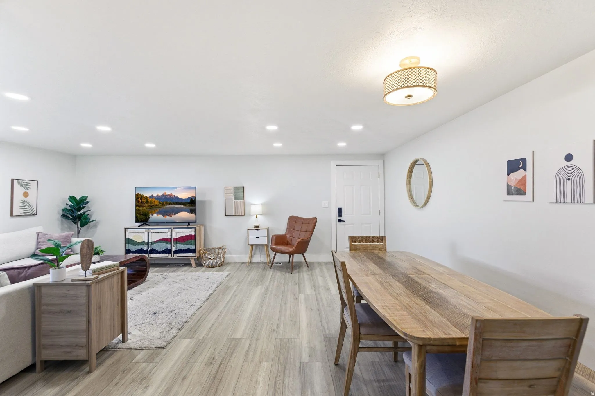 Open-concept living area featuring light wood-finish flooring, recessed lighting, and a contemporary ceiling fixture