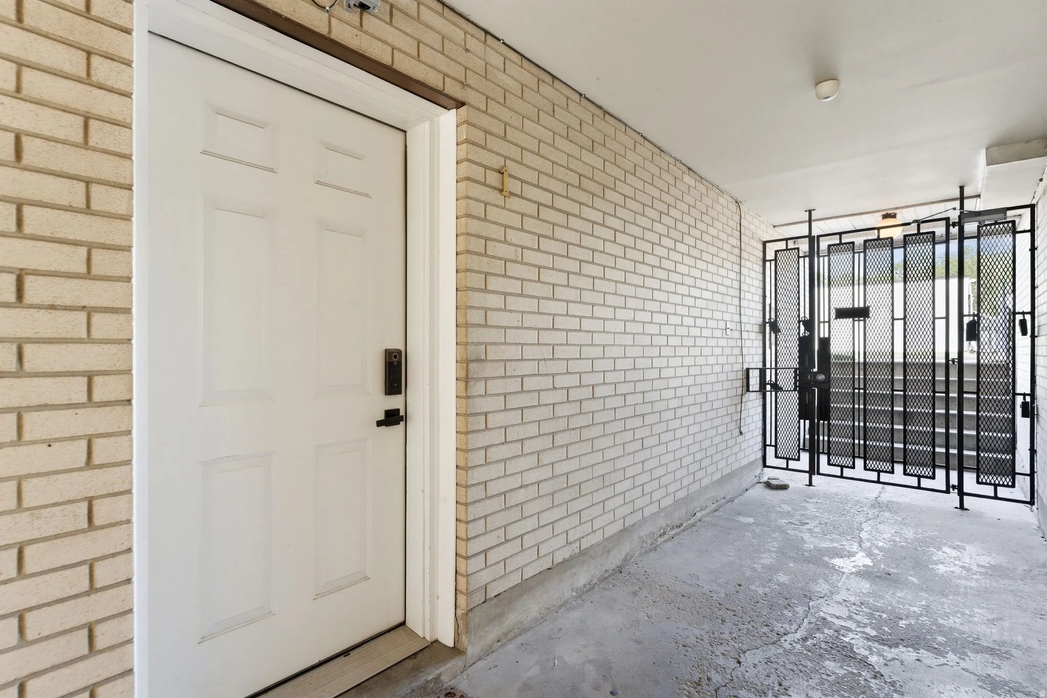 White panel door with black hardware, set within a light-colored brick exterior