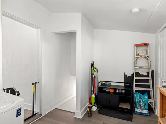 White wall finishes with wood-finish flooring, featuring a doorway and an open alcove