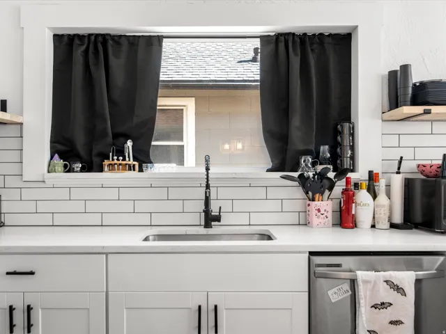 Kitchen featuring a single basin stainless steel sink, matte black faucet, and white subway tile backsplash