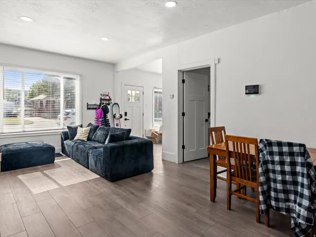Spacious living area featuring light wood-finish flooring, recessed lighting, and a large window with blinds