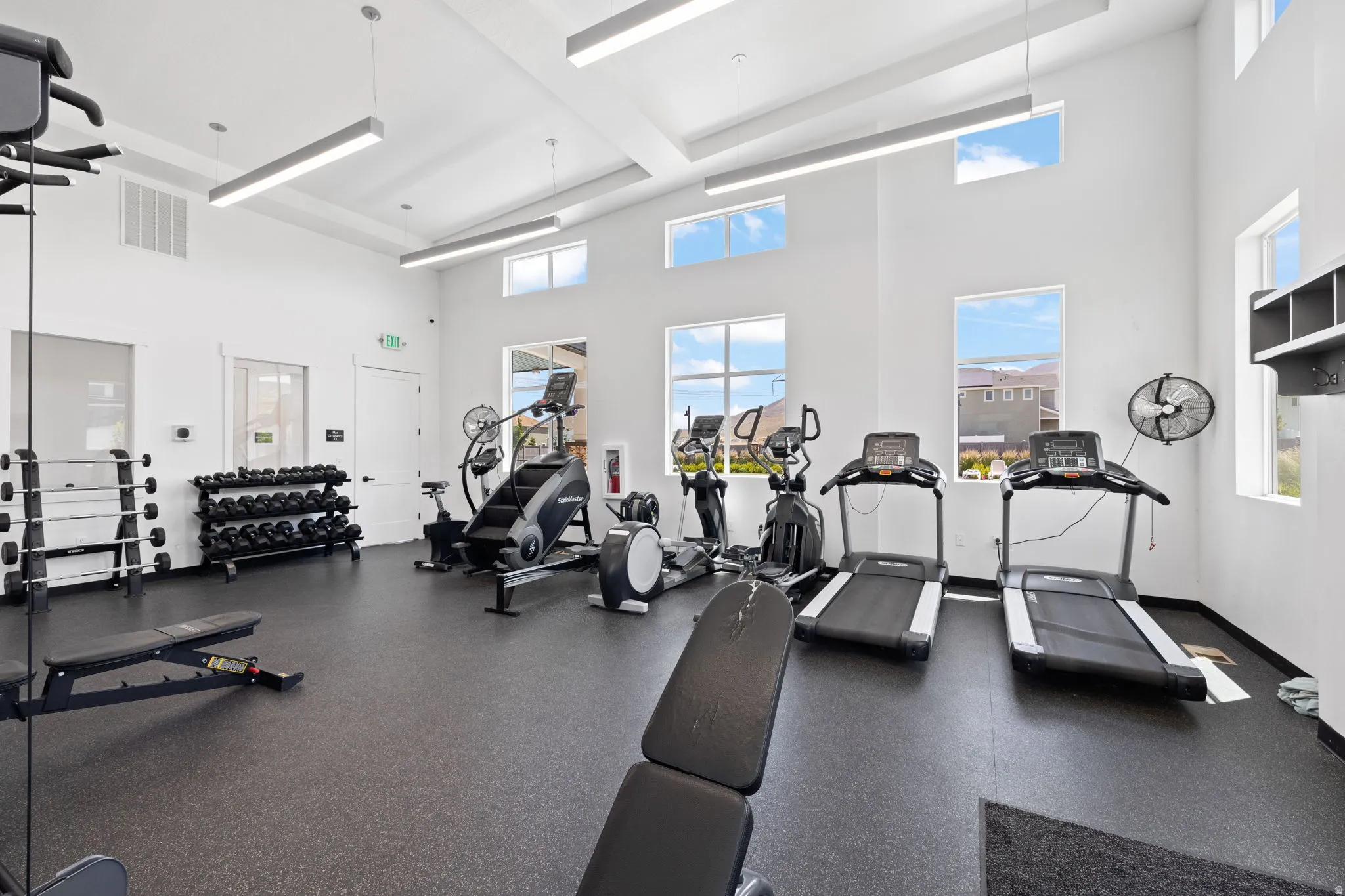 Fitness center featuring ample space, rubber flooring, and high ceilings with recessed linear lighting