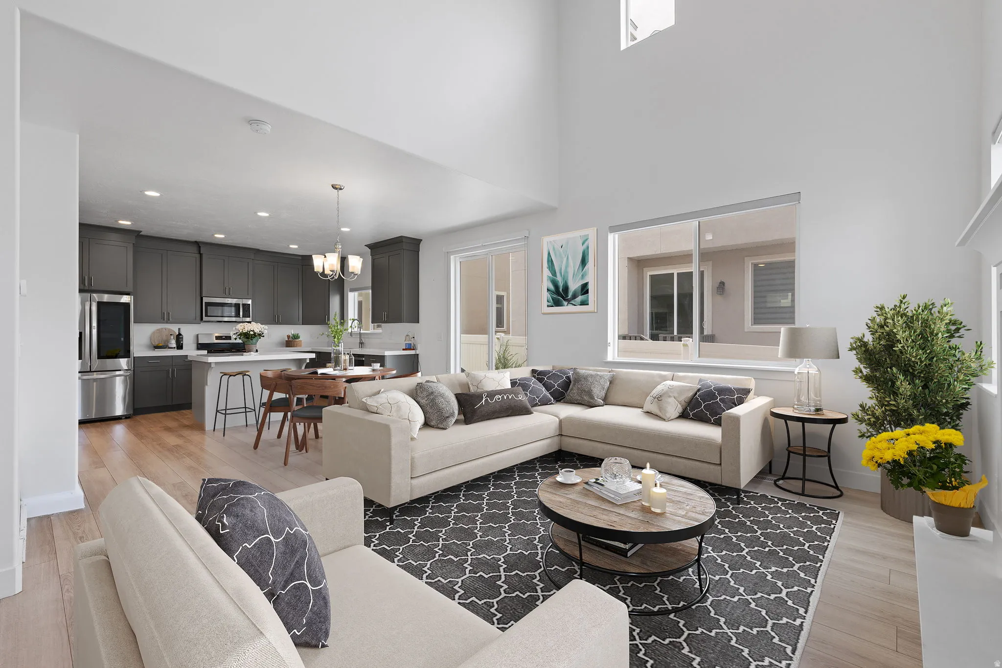 Open-concept living space featuring high ceilings, wood-finish flooring, and ample natural light from multiple windows