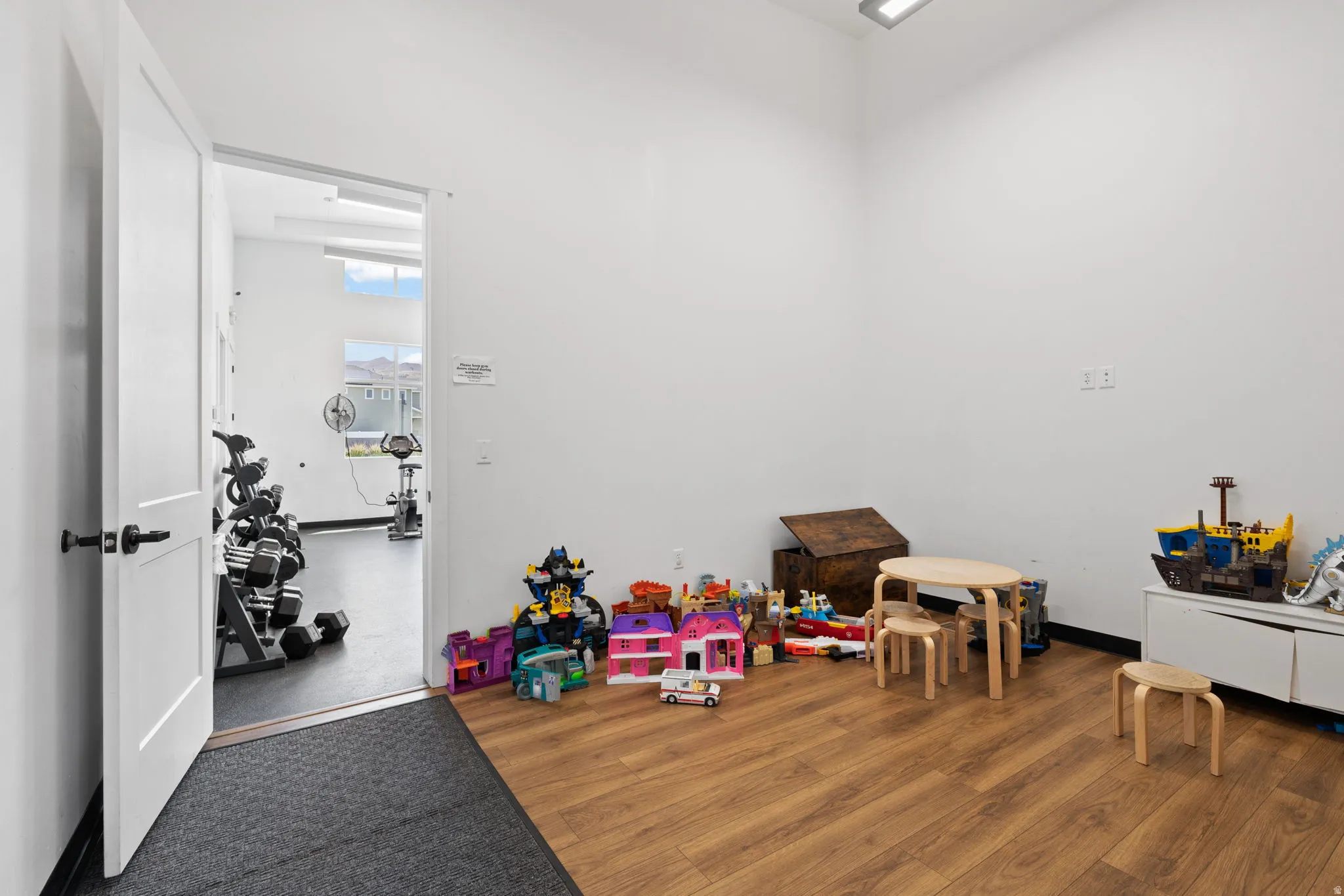 Spacious room featuring wood-finish flooring, white walls, and contemporary overhead lighting