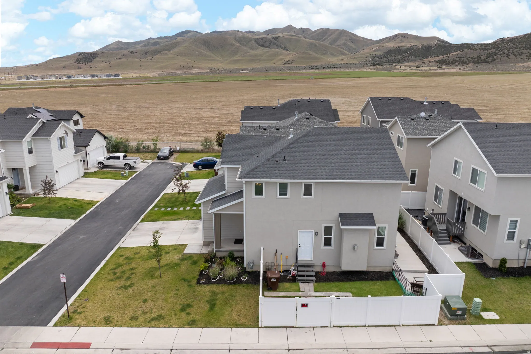 Contemporary two-story residence featuring a light-toned exterior, dark shingle roof, and multiple windows
