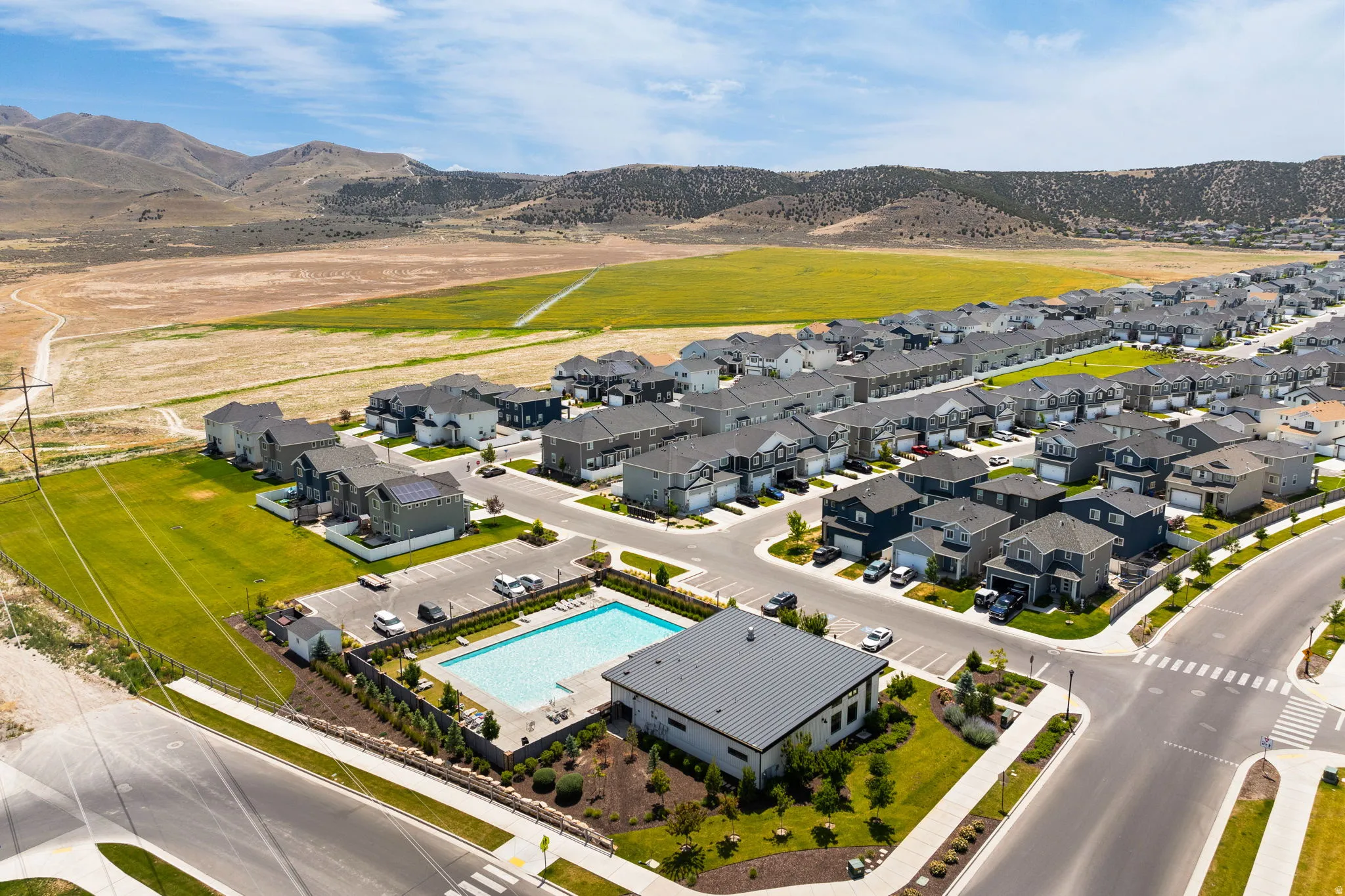 Aerial perspective showcasing a residential community with contemporary homes, a central swimming pool, and dedicated parking