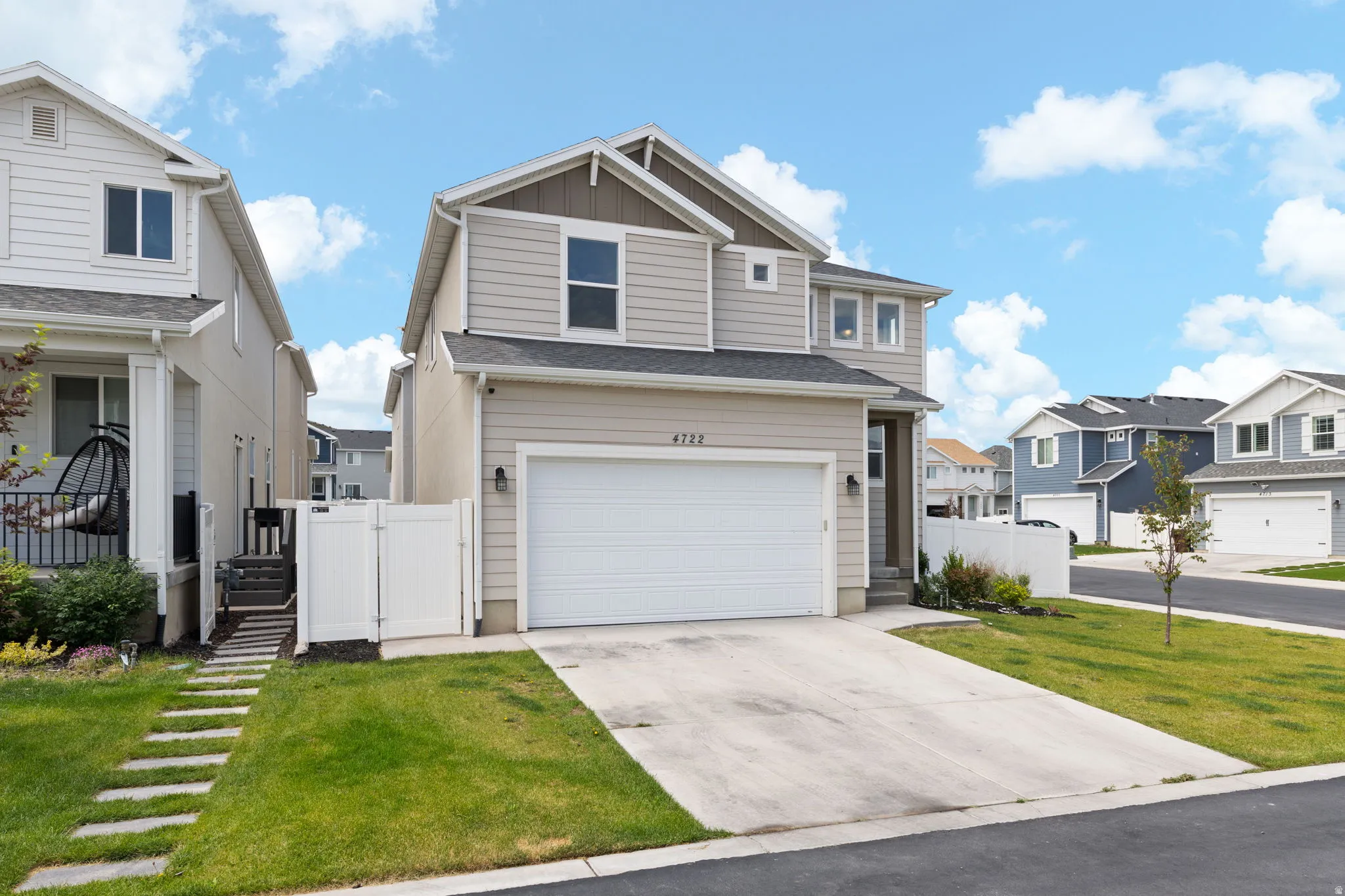 Two-story residence featuring light-toned siding with contrasting trim, an attached two-car garage, and a concrete driveway