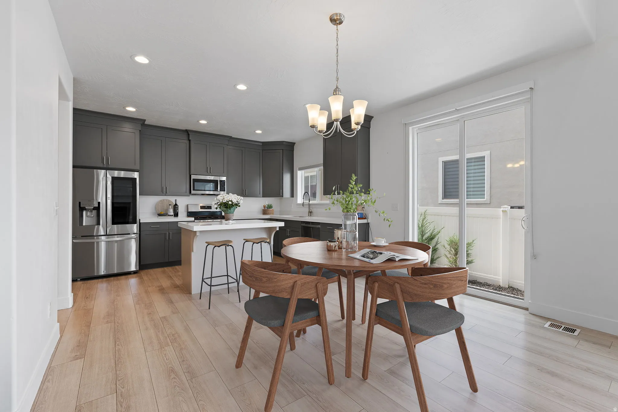 Open-concept dining area featuring light wood-finish flooring and a contemporary chandelier
