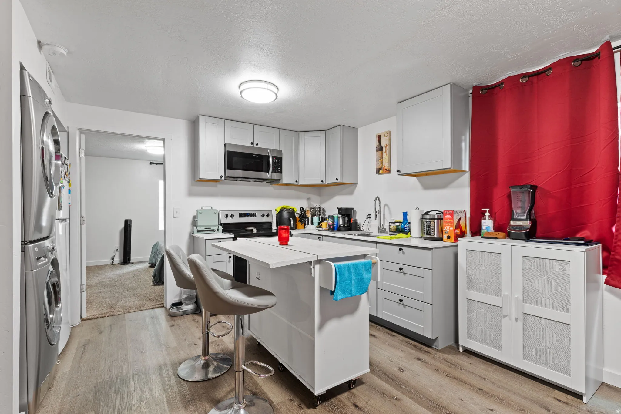 Kitchen featuring wood-finish flooring, light gray cabinetry, stainless steel appliances, and a mobile island with seating