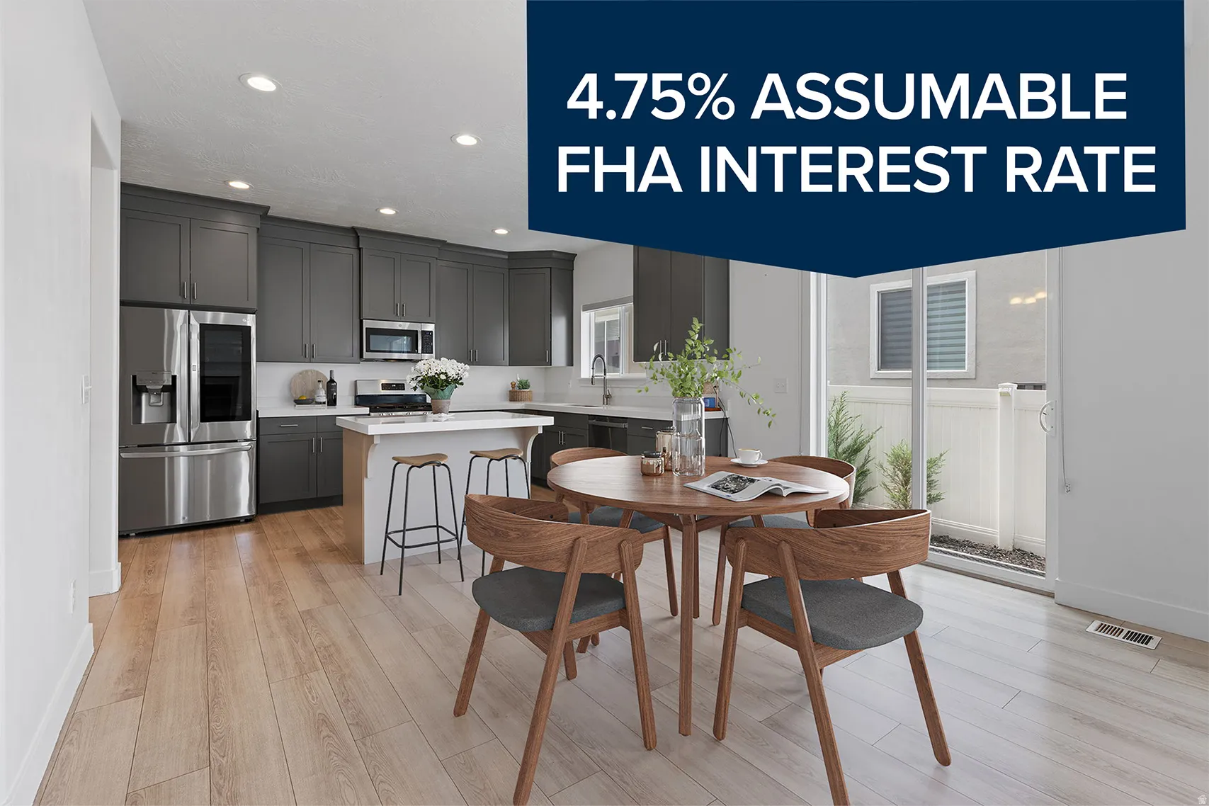 Open-concept kitchen and dining area featuring light wood-finish flooring, dark grey cabinetry, stainless steel appliances, a kitchen island with seating, and sliding glass doors to the exterior