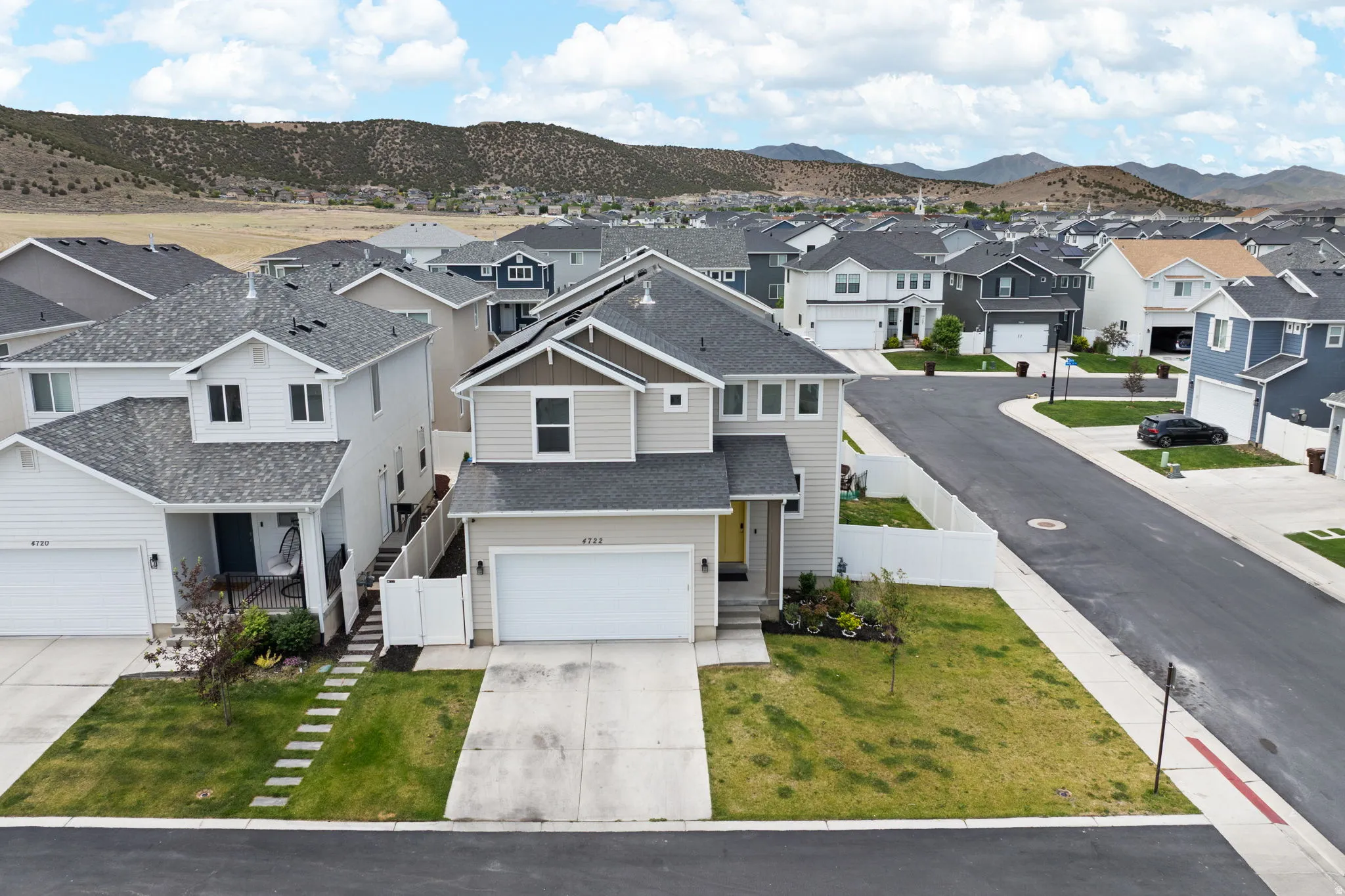 Two-story residence featuring light beige siding with dark trim accents and an attached two-car garage