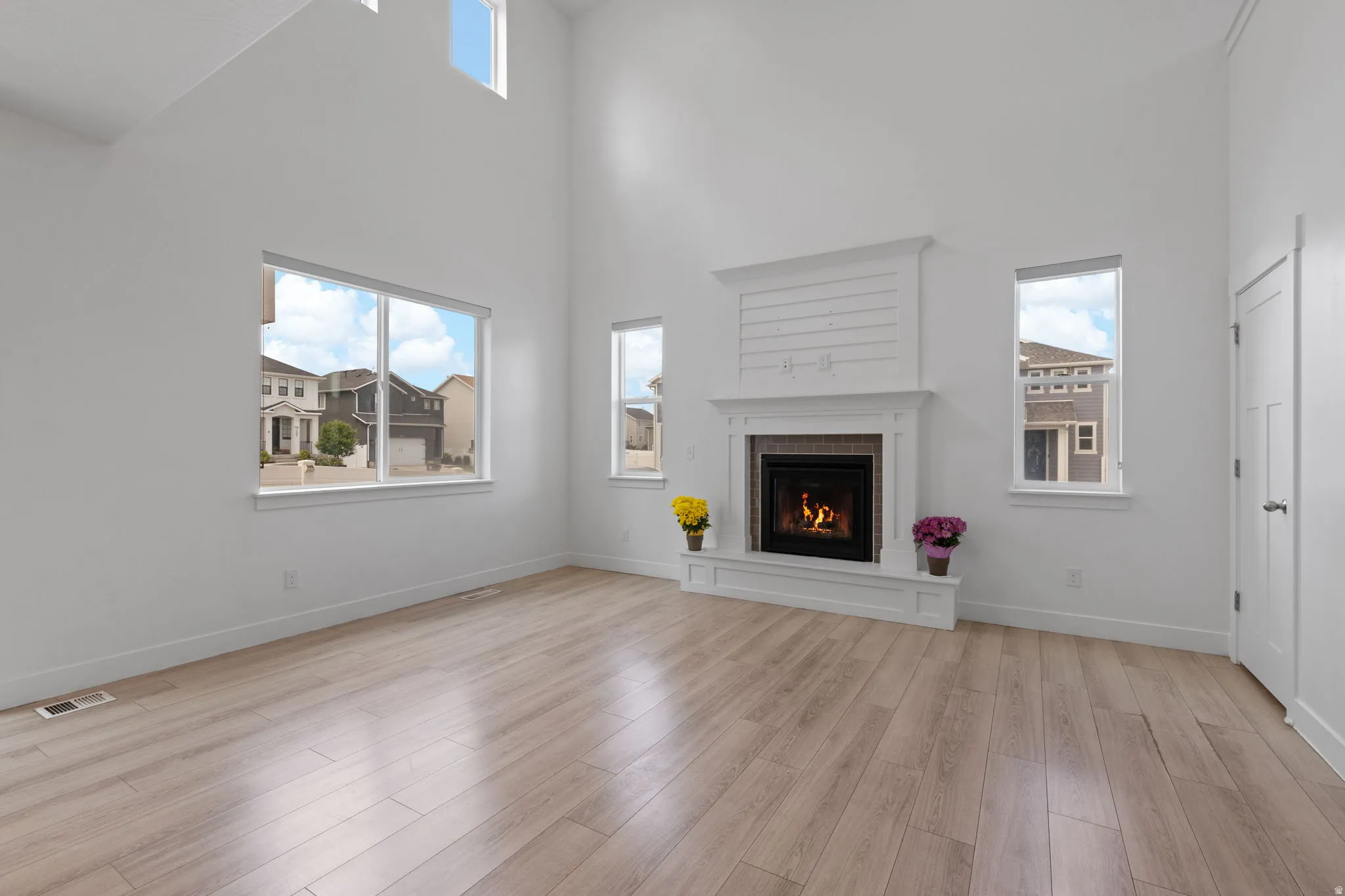 Vaulted ceilings with high windows complement a fireplace featuring a shiplap accent