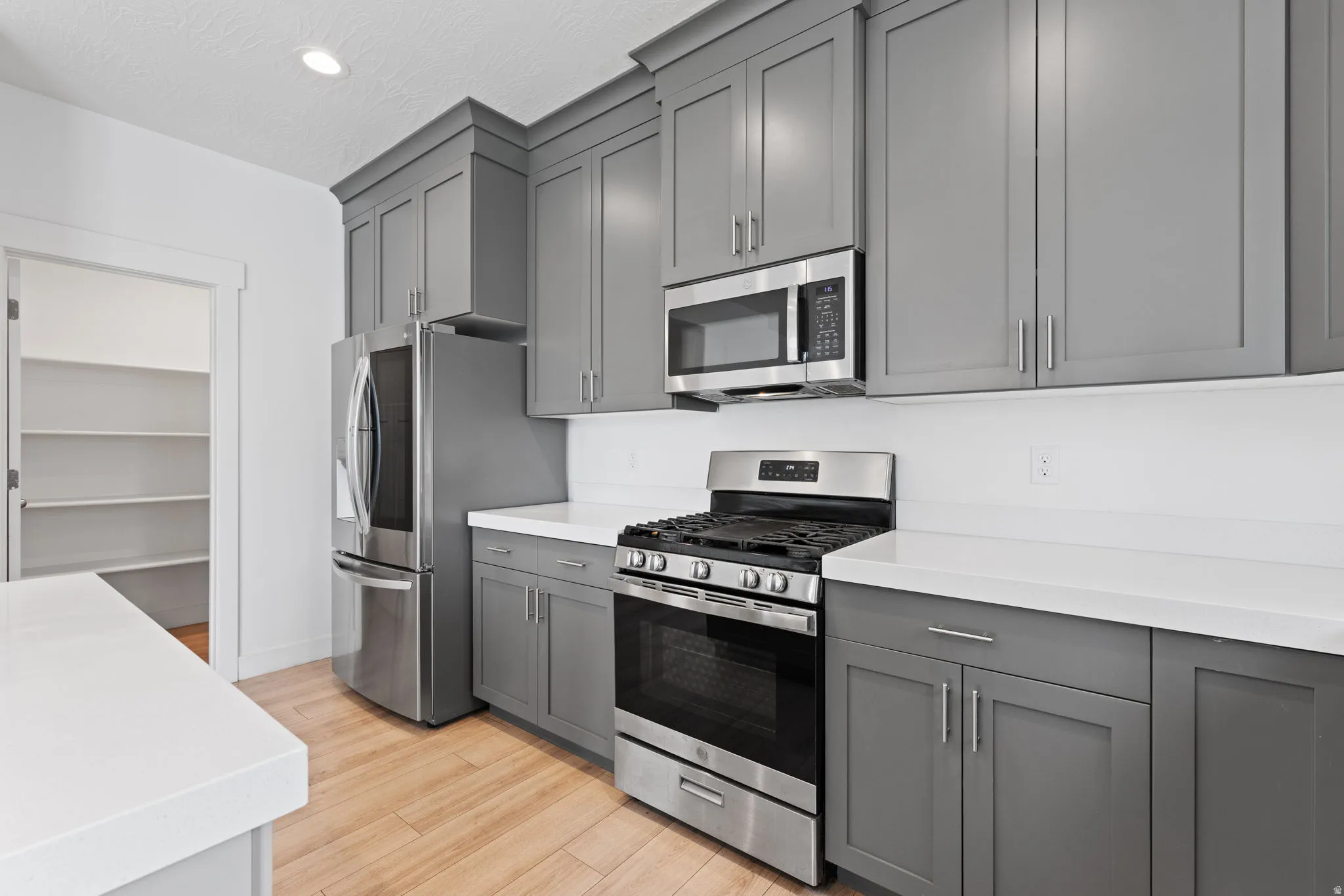 Kitchen featuring light wood-finish flooring, white countertops, and gray cabinetry
