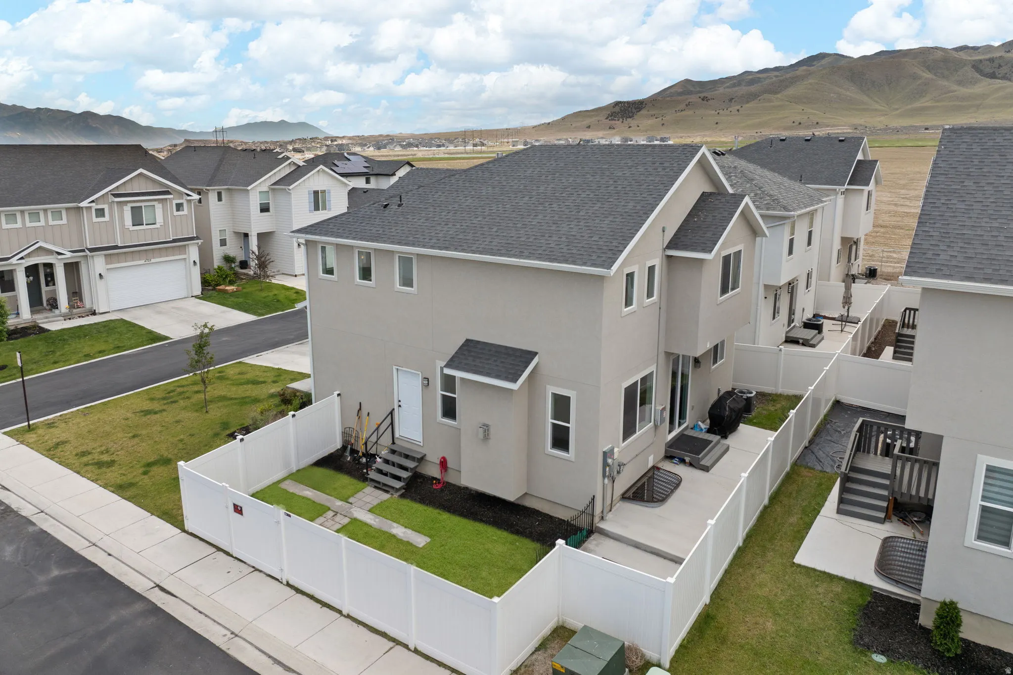 Modern townhouse exterior featuring a light-colored stucco finish and a dark shingle roof