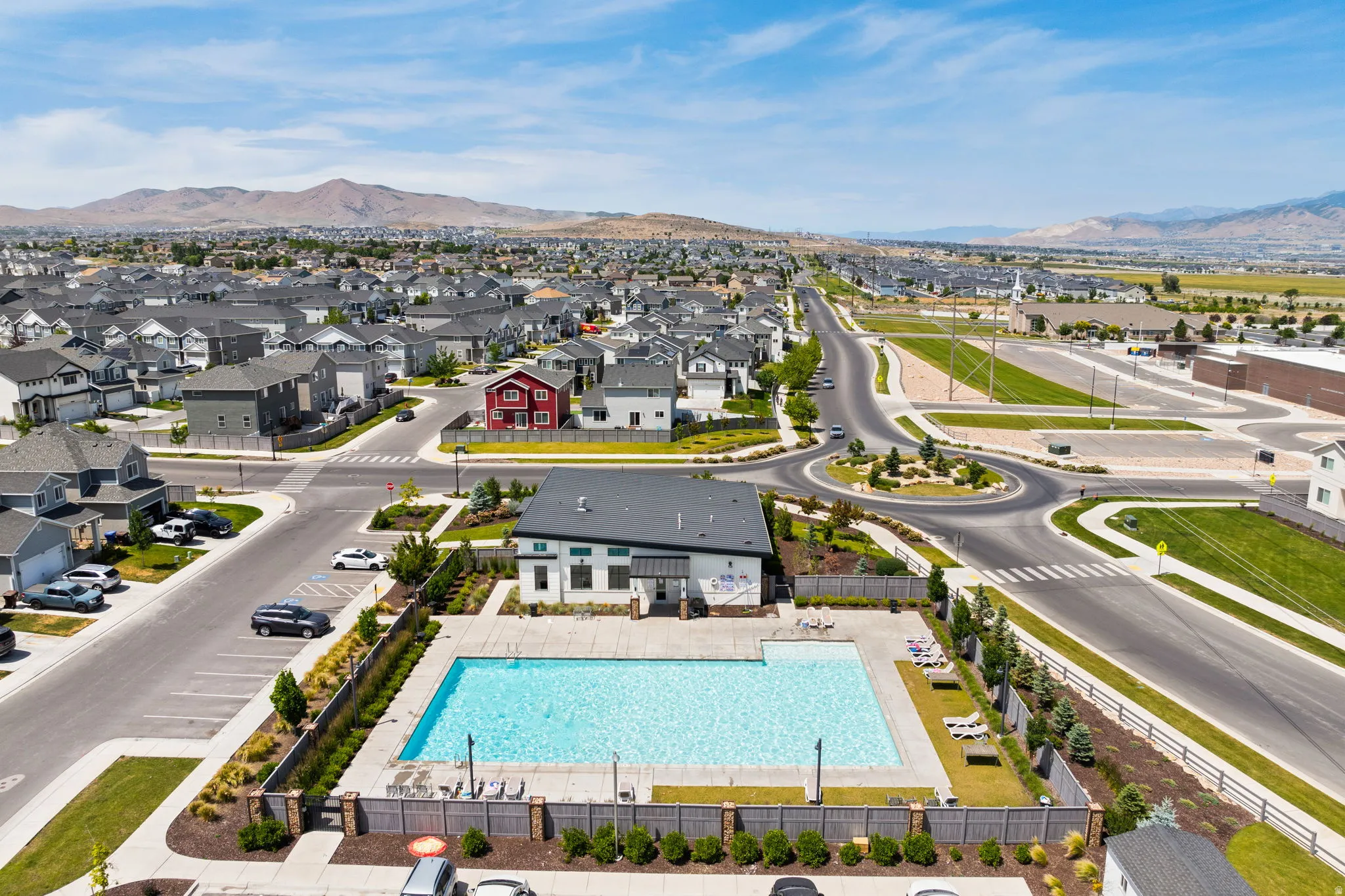 Outdoor swimming pool with surrounding fence and paved patio, situated adjacent to a contemporary building and landscaped grounds