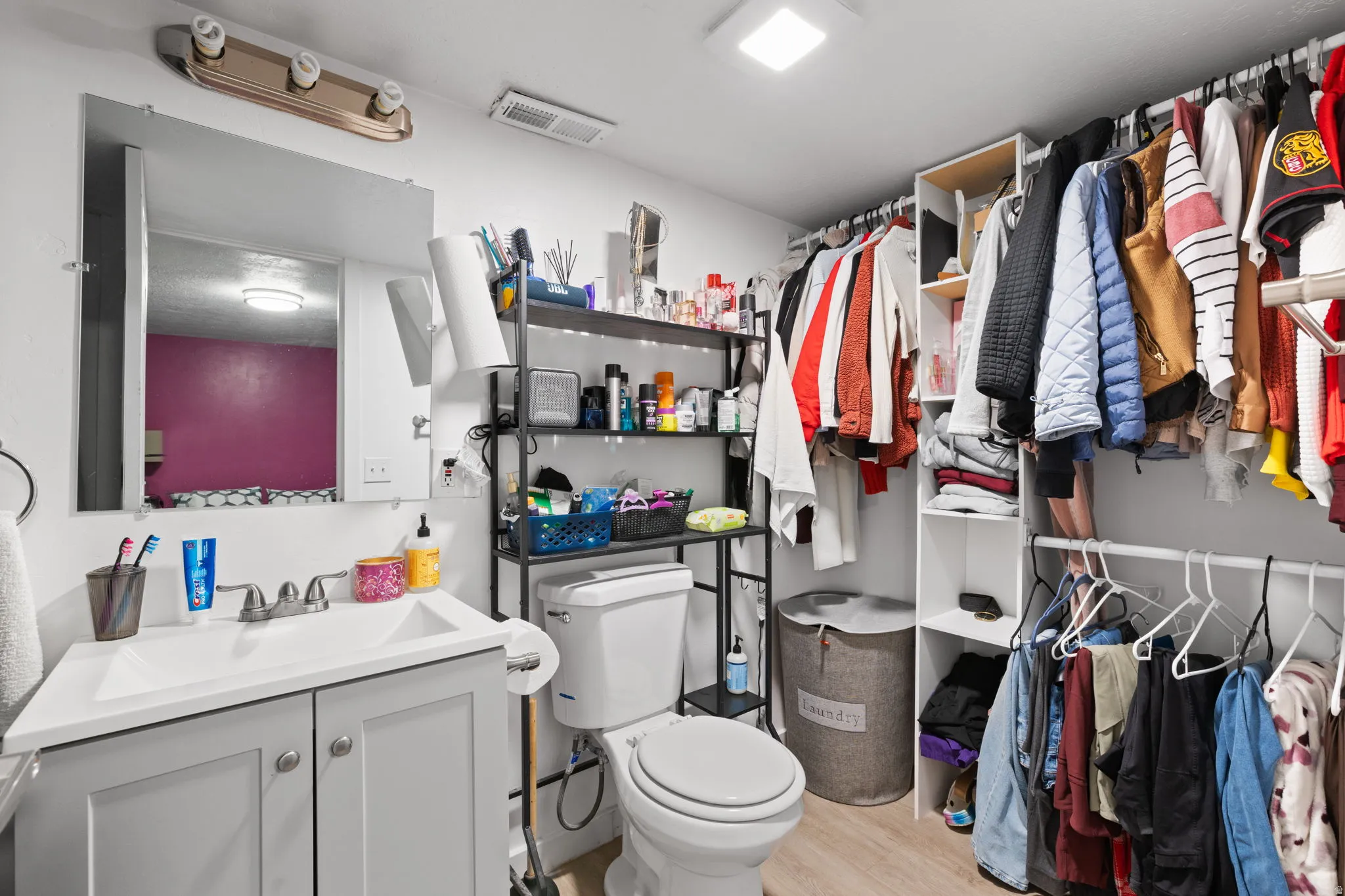 Bathroom featuring a single vanity with a white countertop and light gray cabinetry, a wall-mounted mirror, overhead lighting, and a white toilet