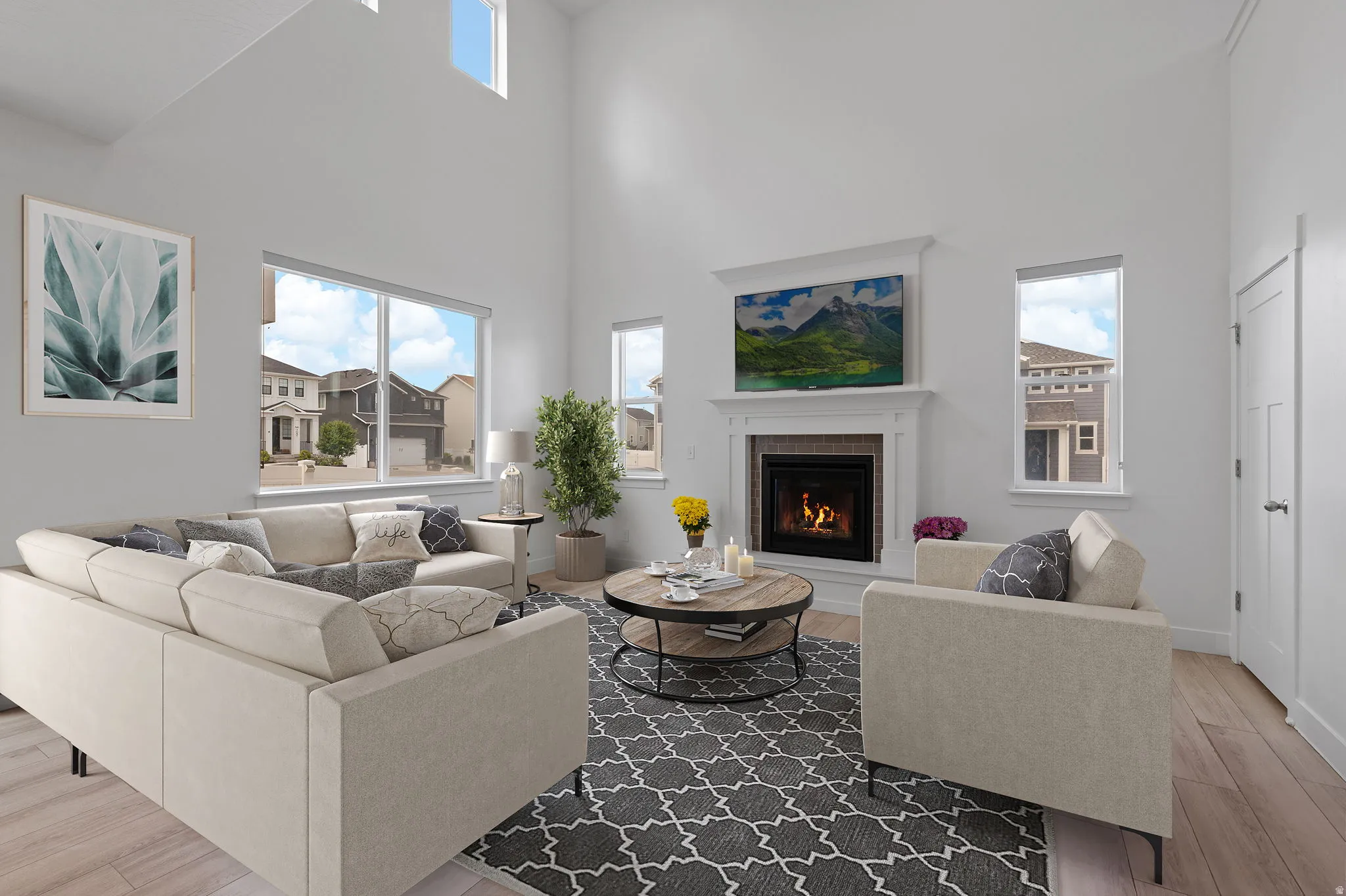 Spacious living area featuring high vaulted ceilings, large windows, a built-in fireplace with a stone surround, and light wood-finish flooring