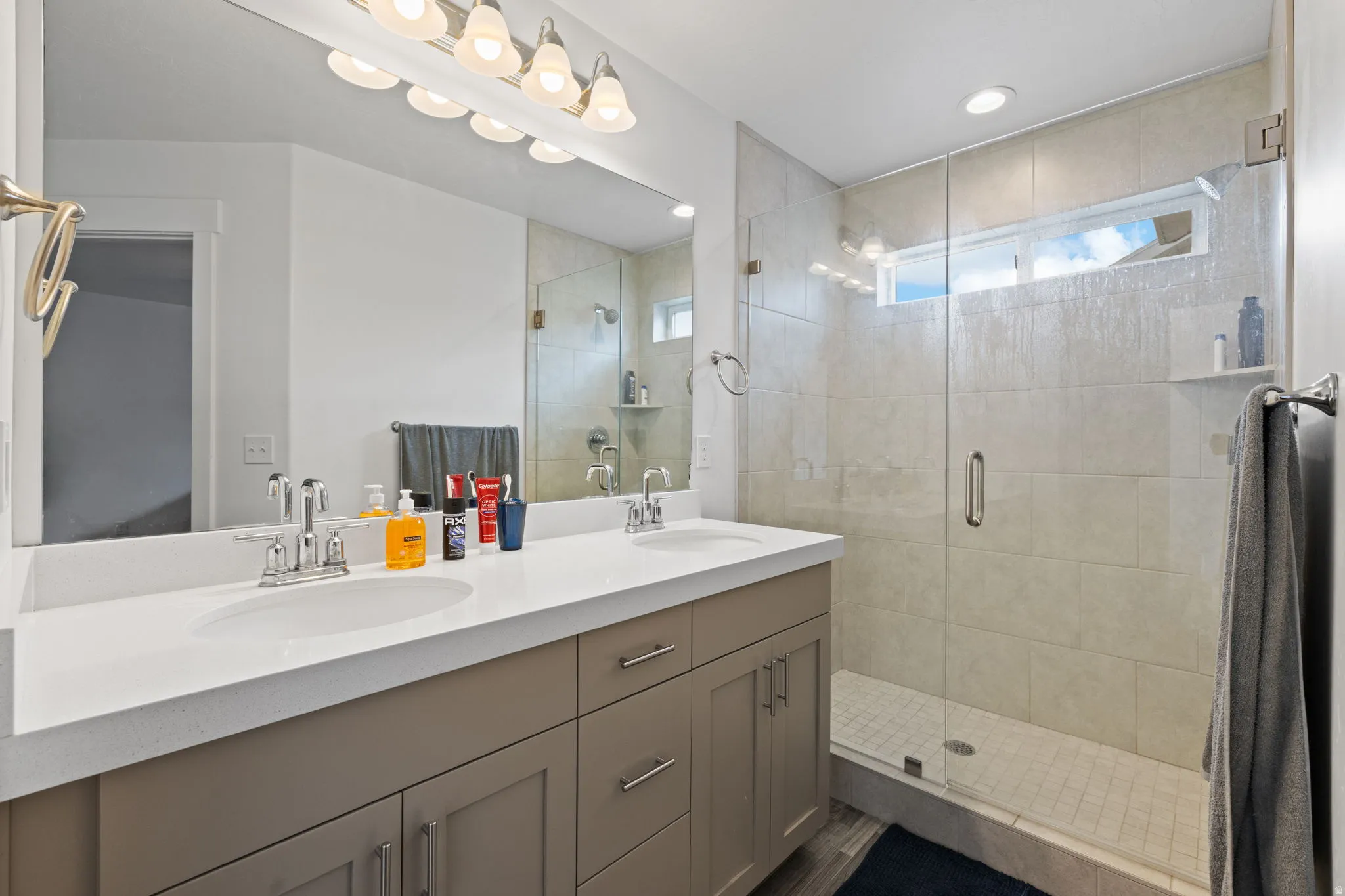 Bathroom featuring a dual vanity with undermount sinks, a quartz-look countertop, and a full-width mirror