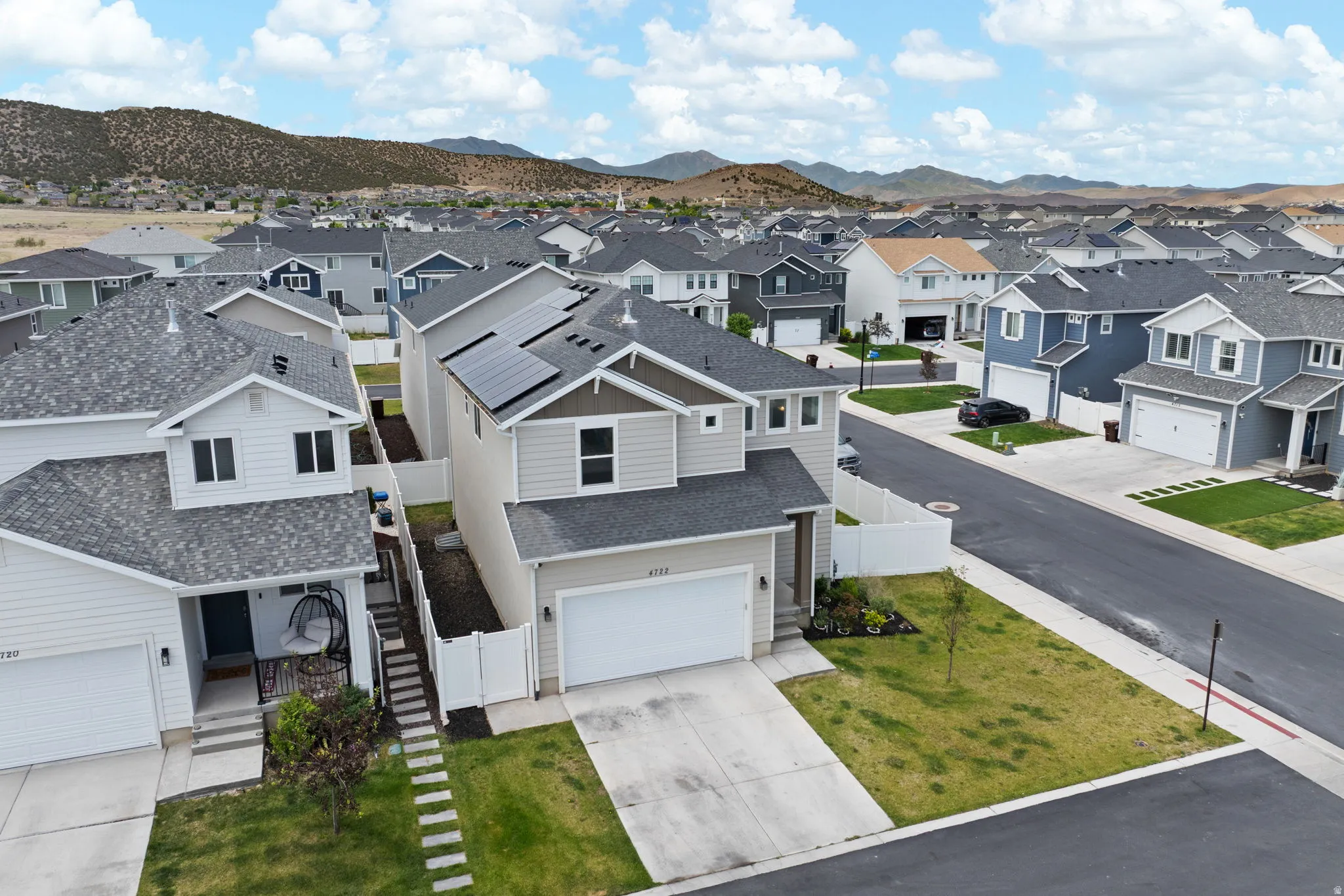 Contemporary residential architecture featuring solar panels, an attached garage, a paved driveway, and a fenced side yard
