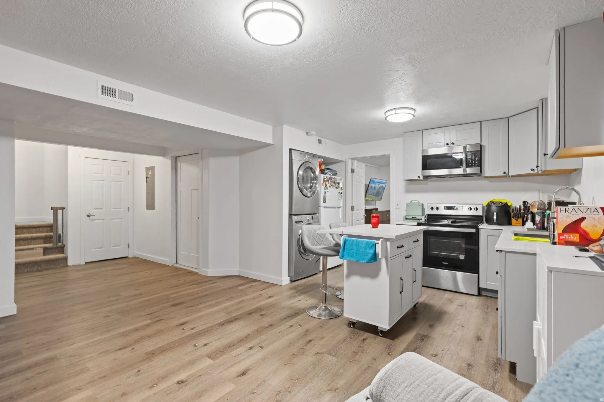 Open-concept living area featuring wood-finish flooring, recessed lighting, and a modern kitchen