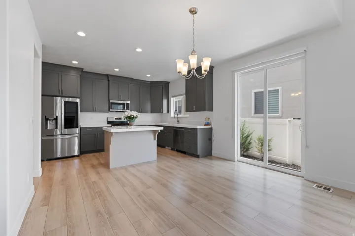 Open-concept kitchen and dining area featuring light wood-finish flooring, a kitchen island with a white countertop, and dark gray cabinetry