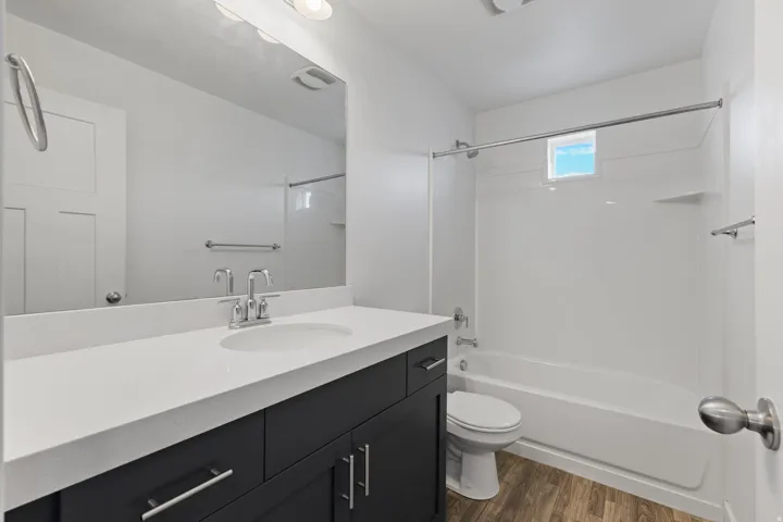 Bathroom featuring a dark wood-finish vanity with a light countertop, a rectangular sink basin, and a chrome faucet