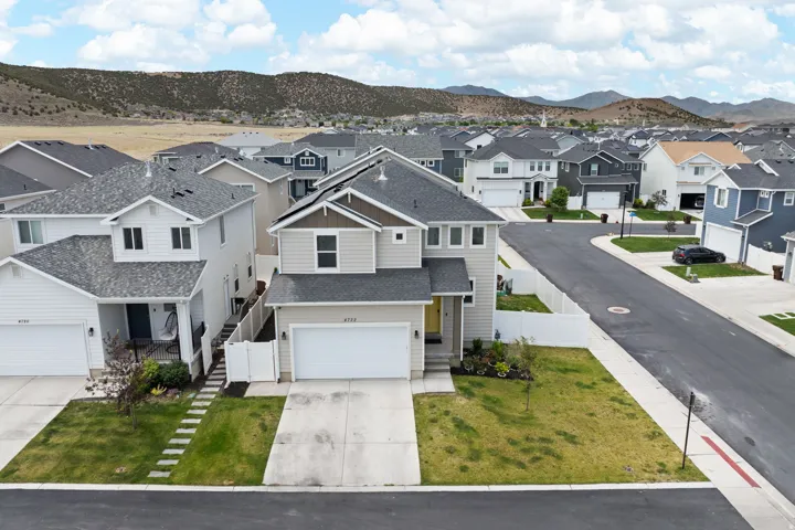 Two-story residence featuring light beige siding with dark trim accents and an attached two-car garage