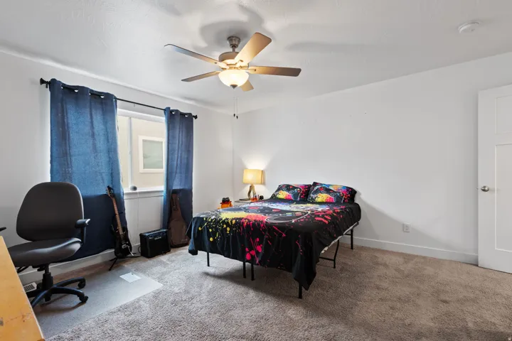 Carpeted room featuring a ceiling fan with integrated lighting, a window with a sill, and a paneled interior door