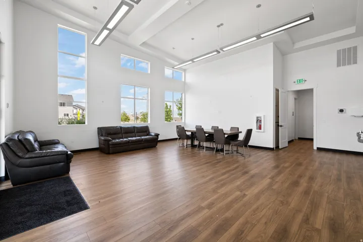 Spacious interior featuring high ceilings, extensive window placement, wood-finish flooring, and contemporary linear pendant lighting fixtures