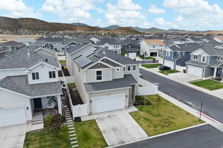 Contemporary residential architecture featuring solar panels, an attached garage, a paved driveway, and a fenced side yard