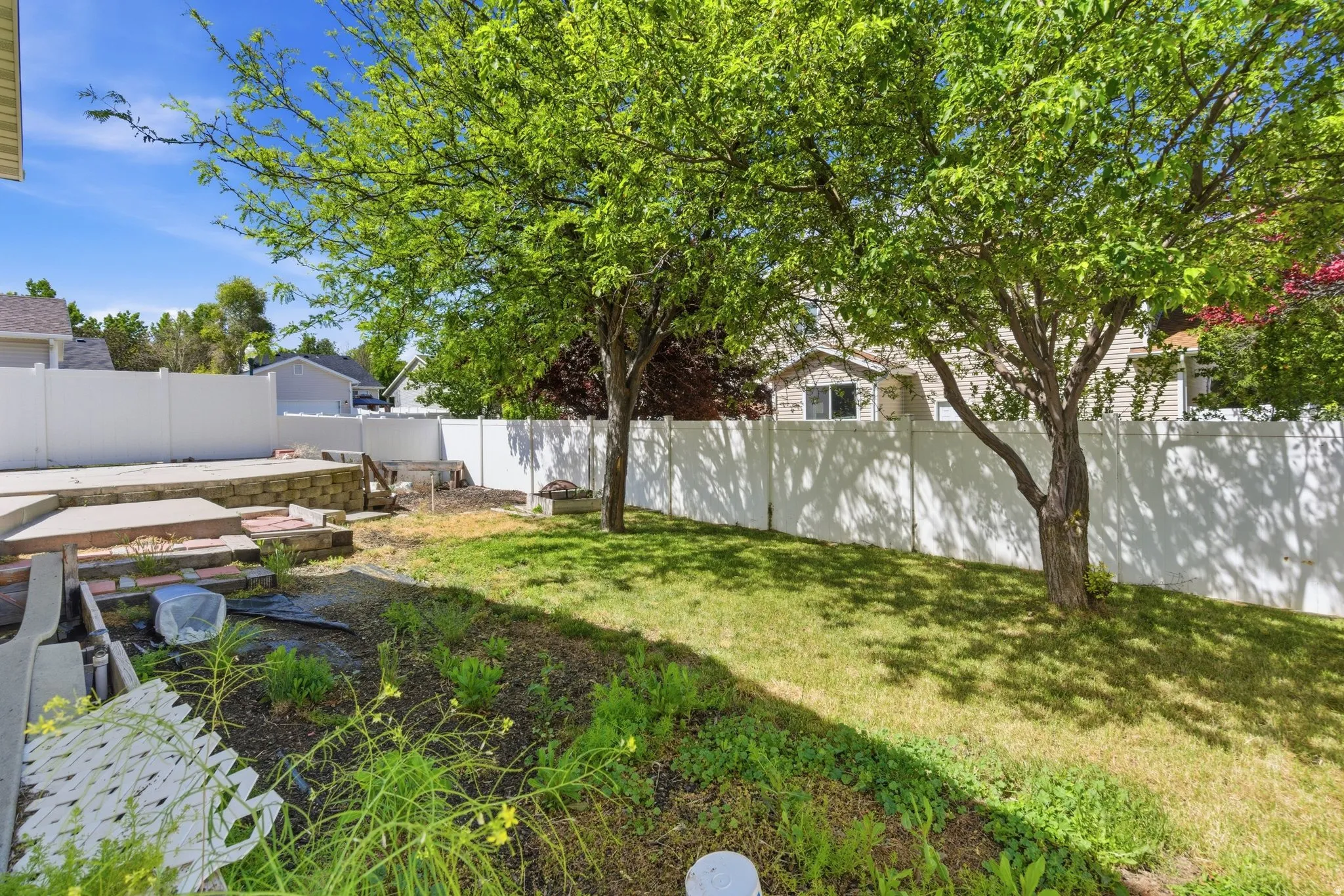 Private backyard featuring a concrete patio, retaining wall, and mature trees