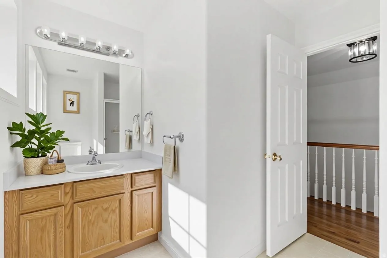 Bathroom vanity featuring a light wood-finish cabinet, white countertop with an integrated sink, and a large mirror