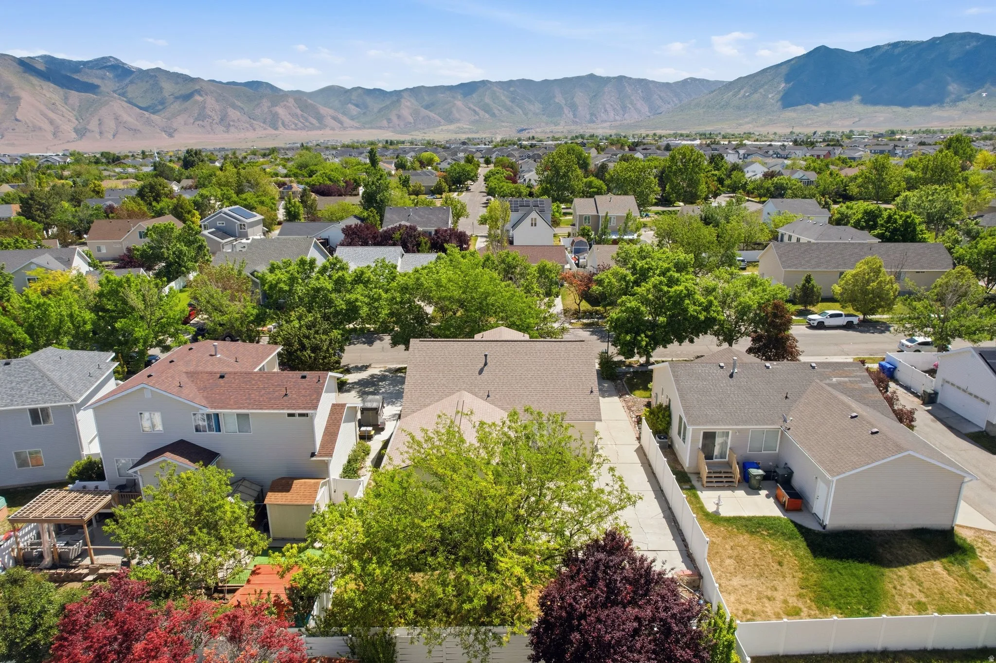 Residential neighborhood featuring a variety of housing styles, established landscaping, mountain backdrop, paved streets, and sidewalks