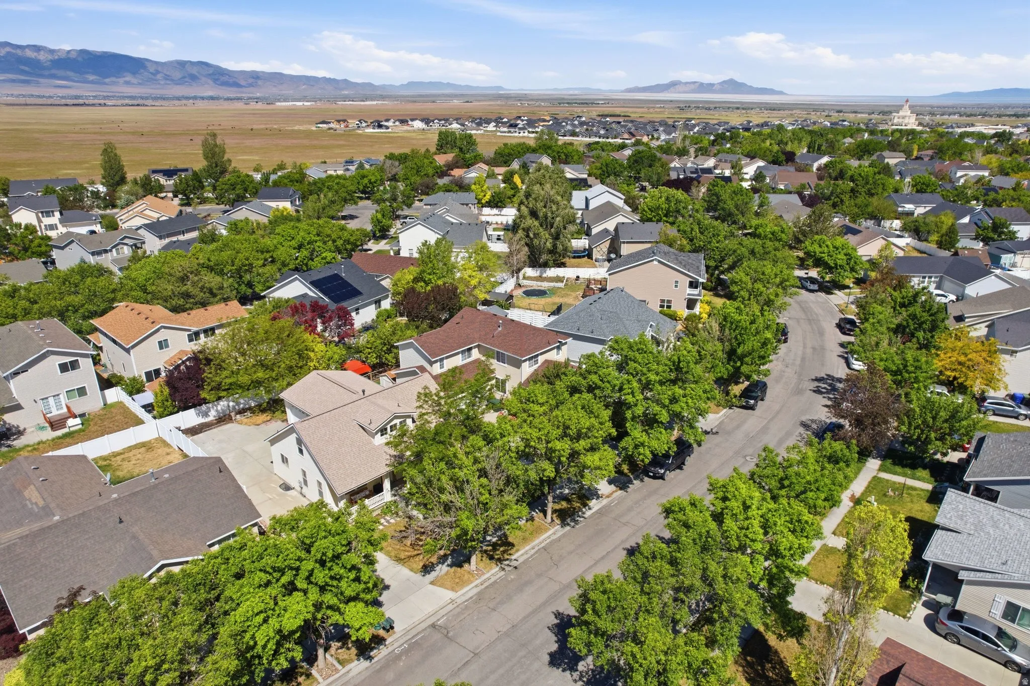 Residential neighborhood featuring mature trees, paved streets, and diverse single-family homes with pitched roofs and various exterior finishes