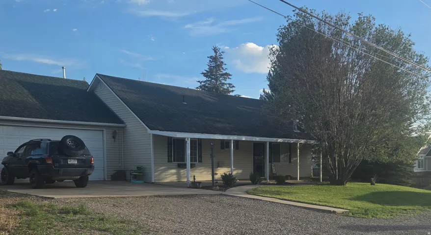 Ranch-style residence featuring light-colored siding and a dark shingle roof