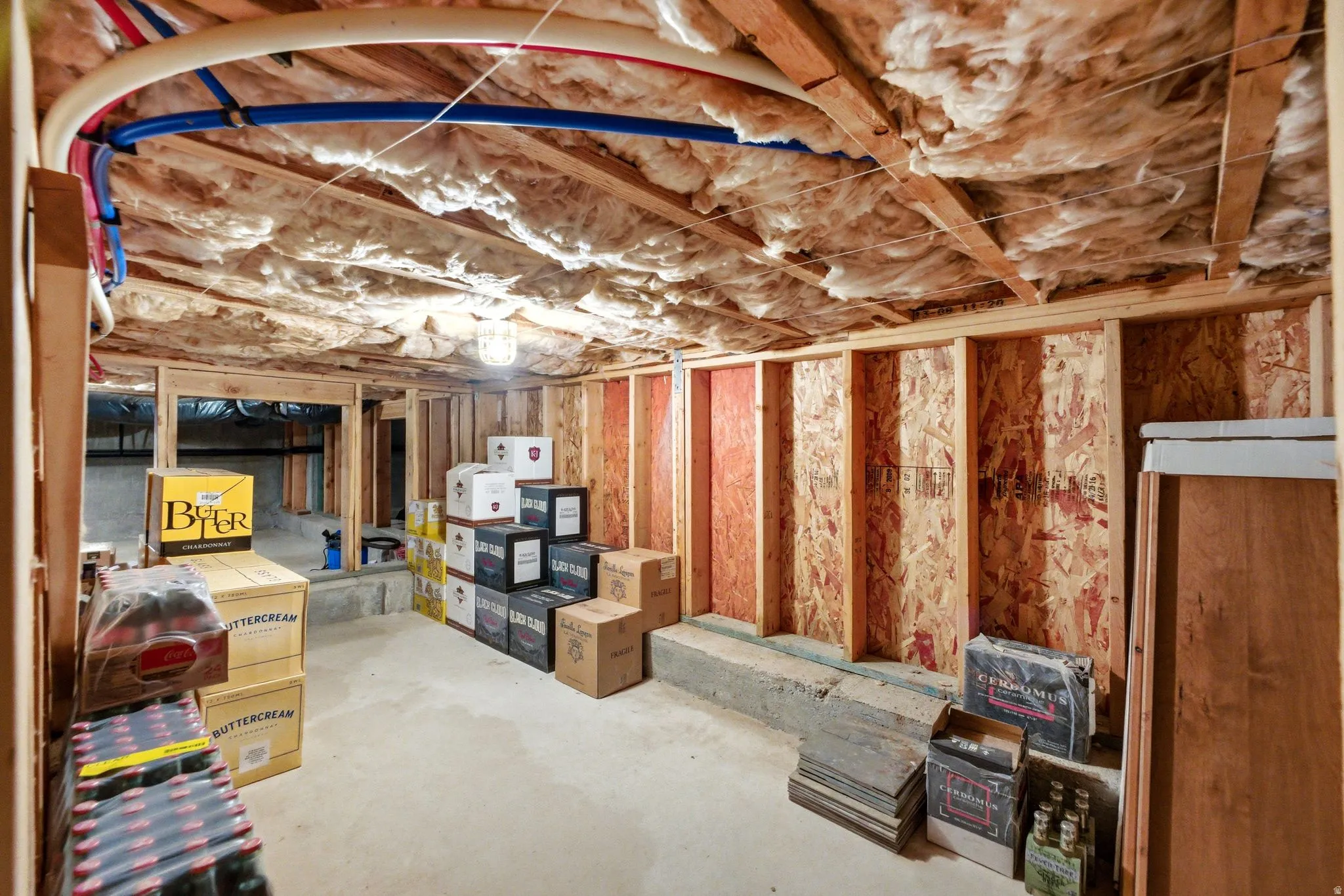Unfinished basement featuring exposed wood joists, ceiling insulation, and concrete flooring
